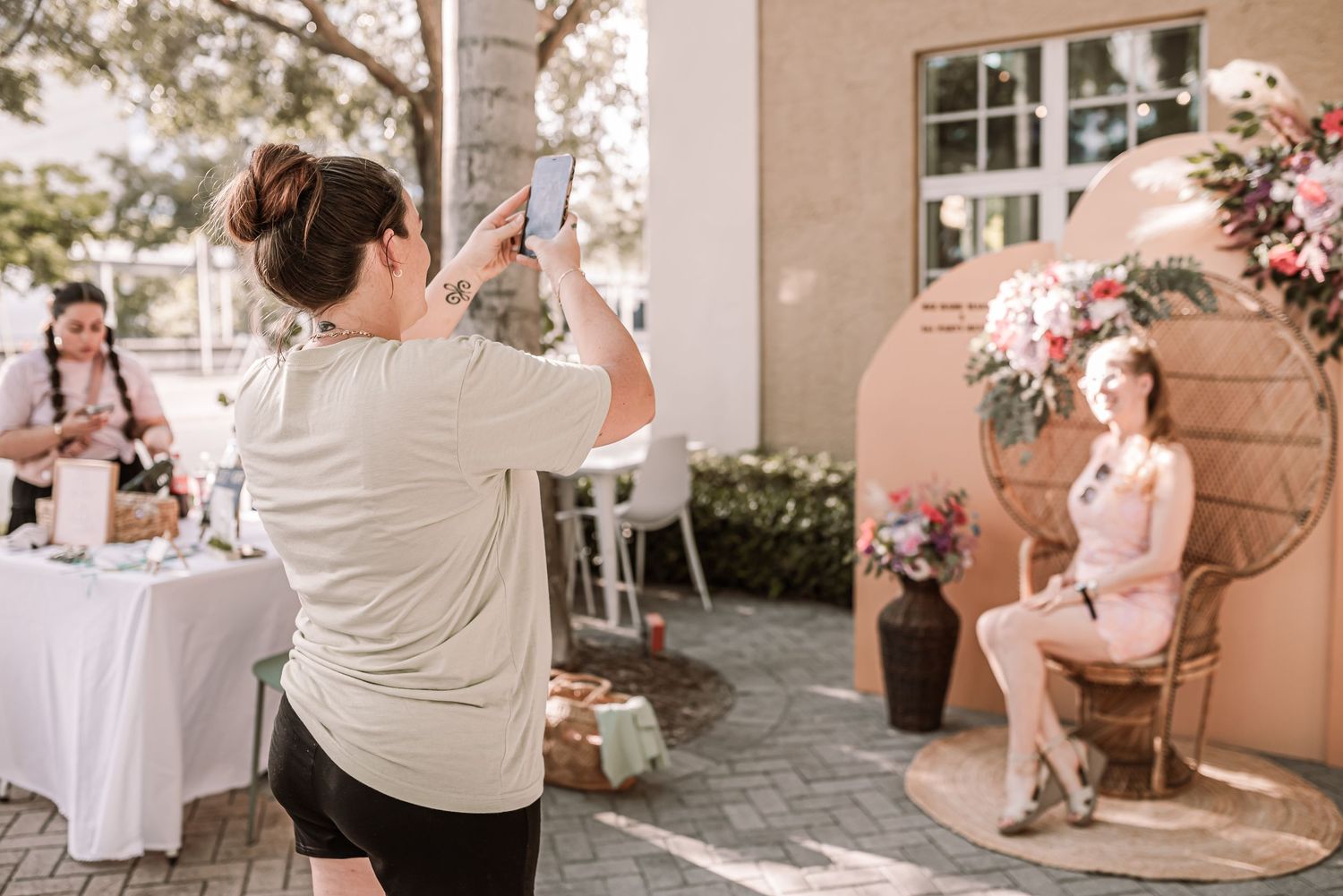 Photographer takes photos of a model at an outdoor venue with floral arrangements and table settings.