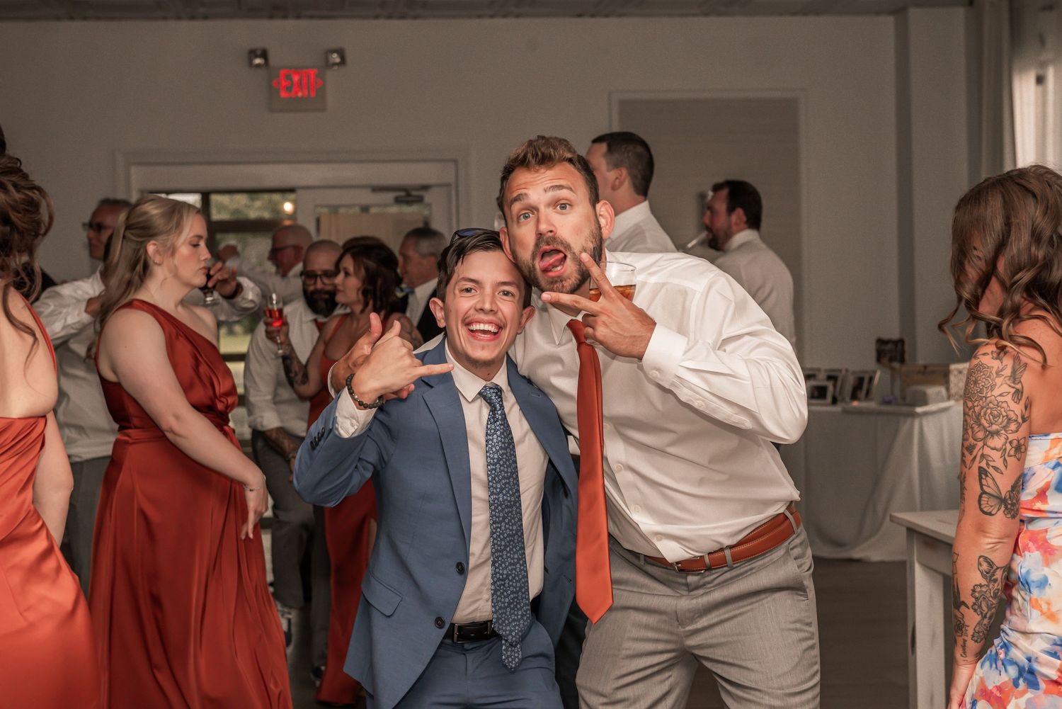 Wedding guests dance enthusiastically together during a celebration at an indoor reception venue.