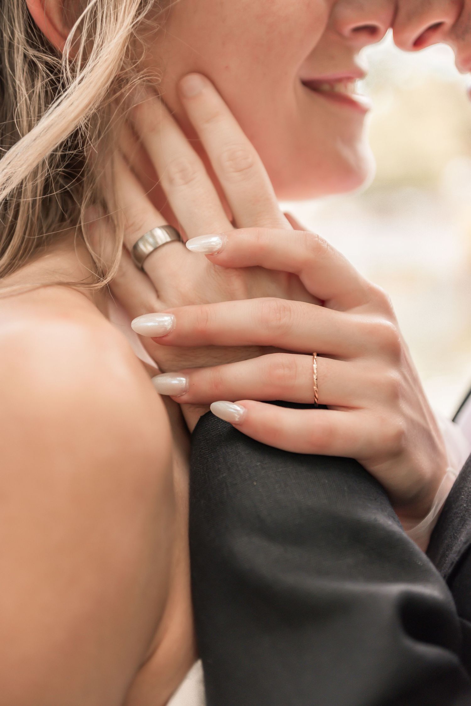 Close-up of a couple embracing, showcasing wedding rings on their hands, symbolizing love and commitment.