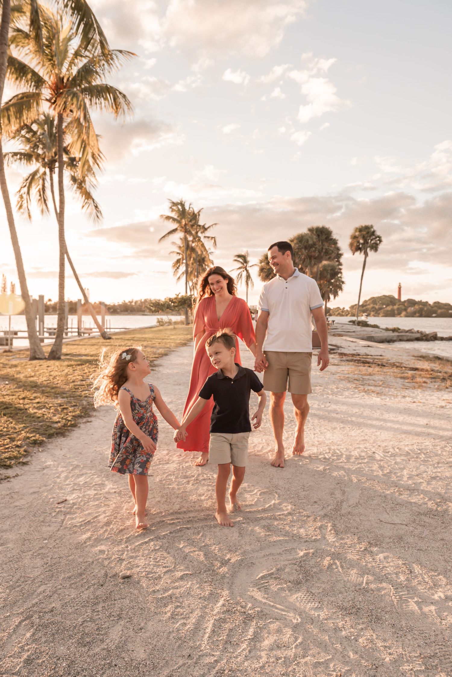 Family enjoying a sunset stroll along a tropical beach with palm trees and golden light.