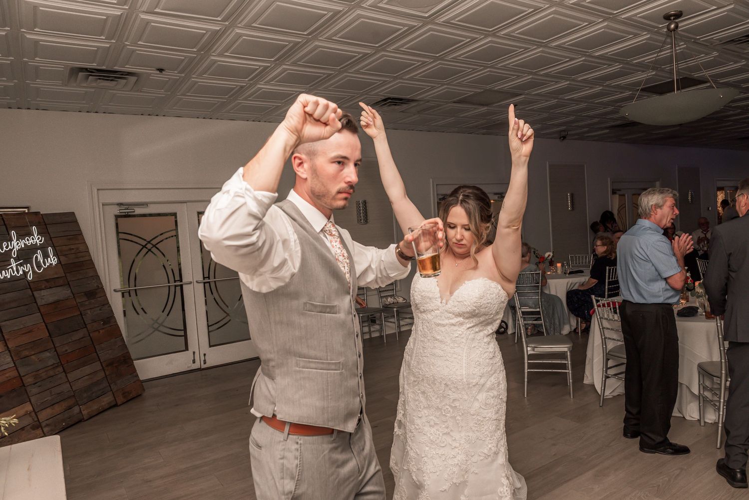 Newlyweds dancing energetically on the dance floor during their wedding reception celebration.