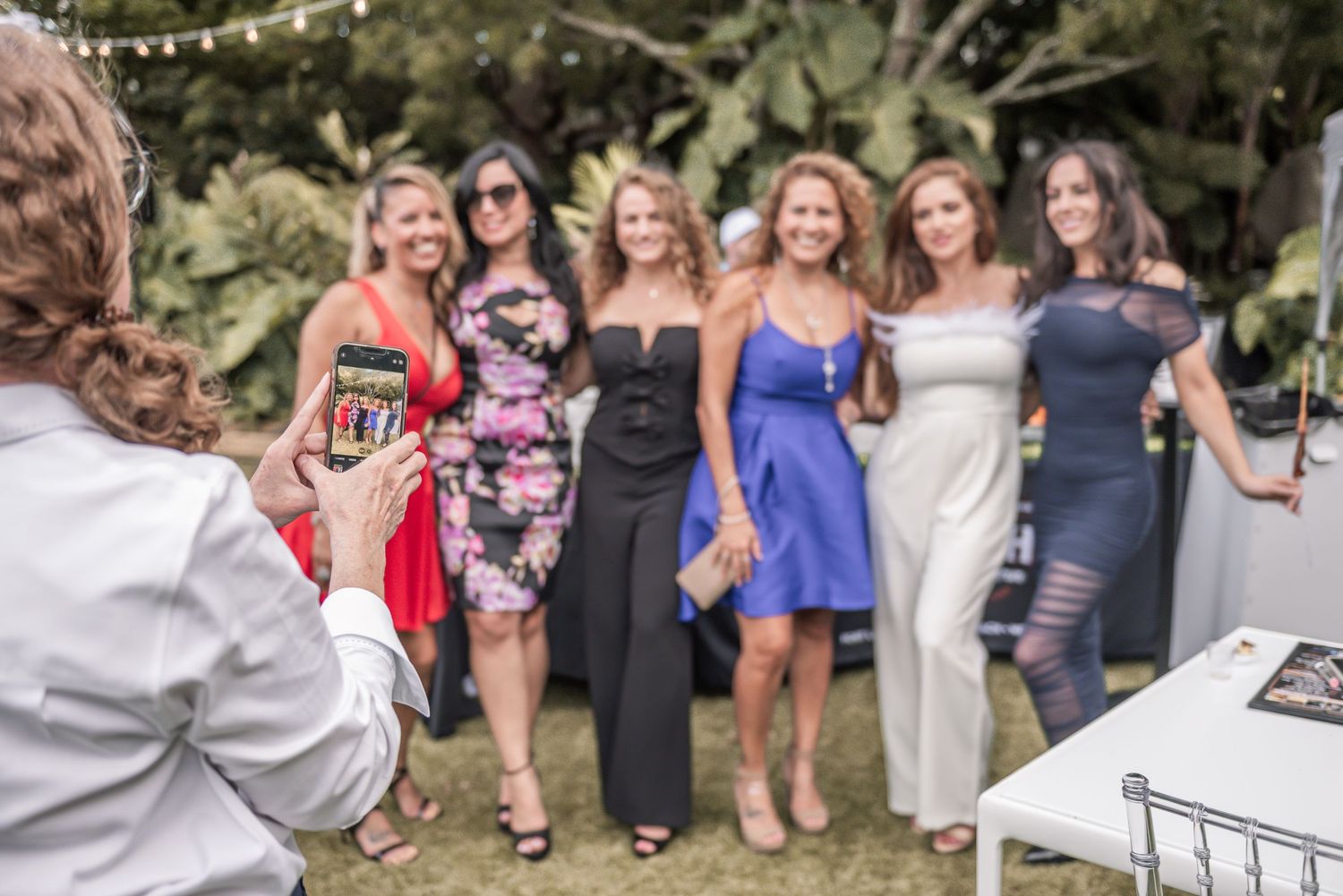 A group of people gathered outdoors in casual attire enjoying a social event on a sunny day.