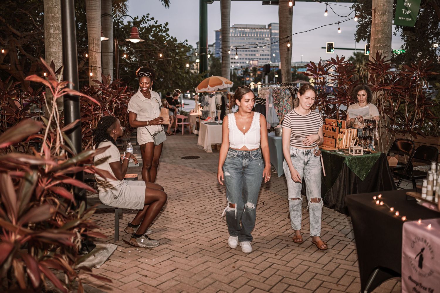 Casual dining atmosphere on an outdoor patio with string lights and tropical plants at sunset.