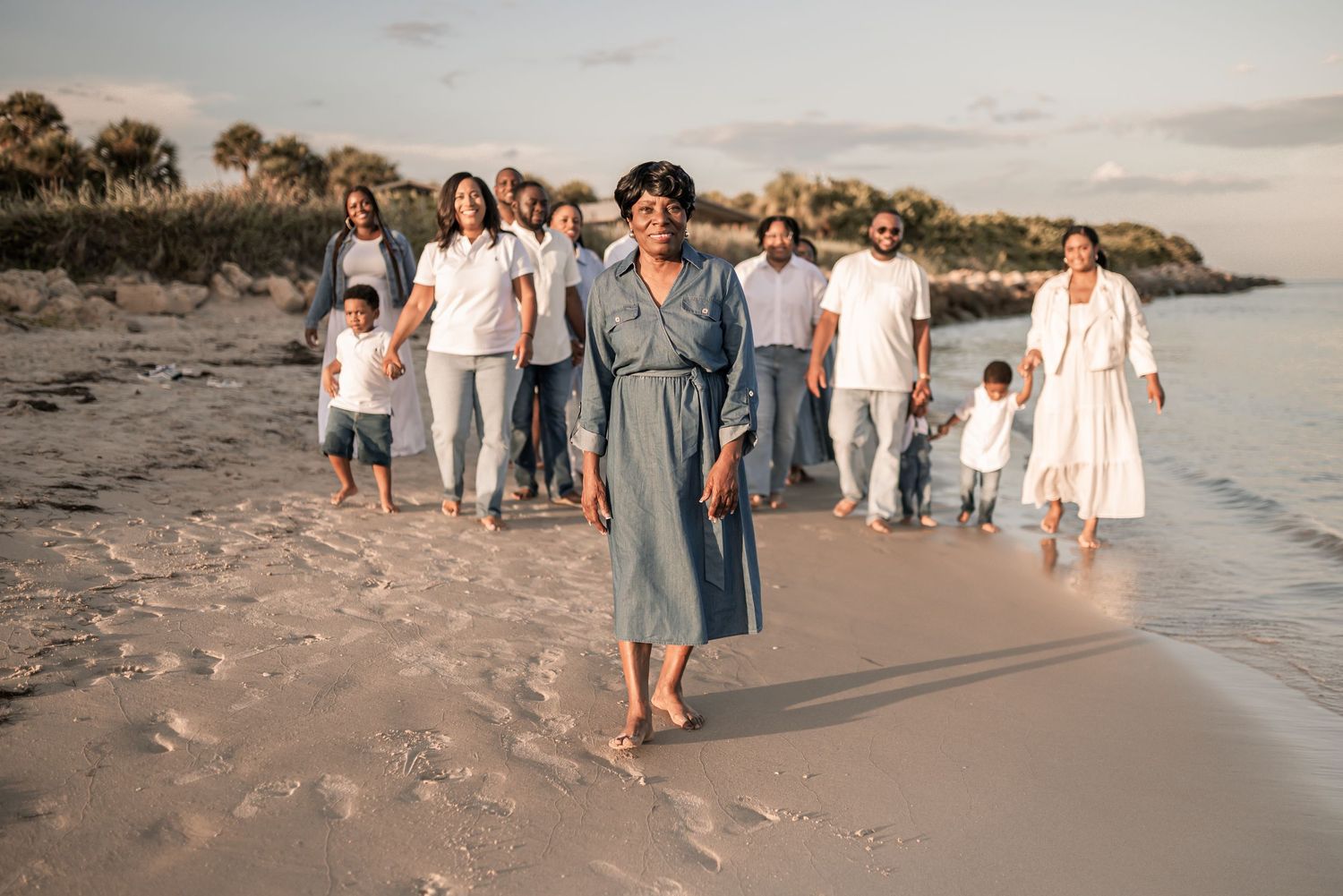 A group walks along a sandy beach at sunset creating a peaceful coastal scene.