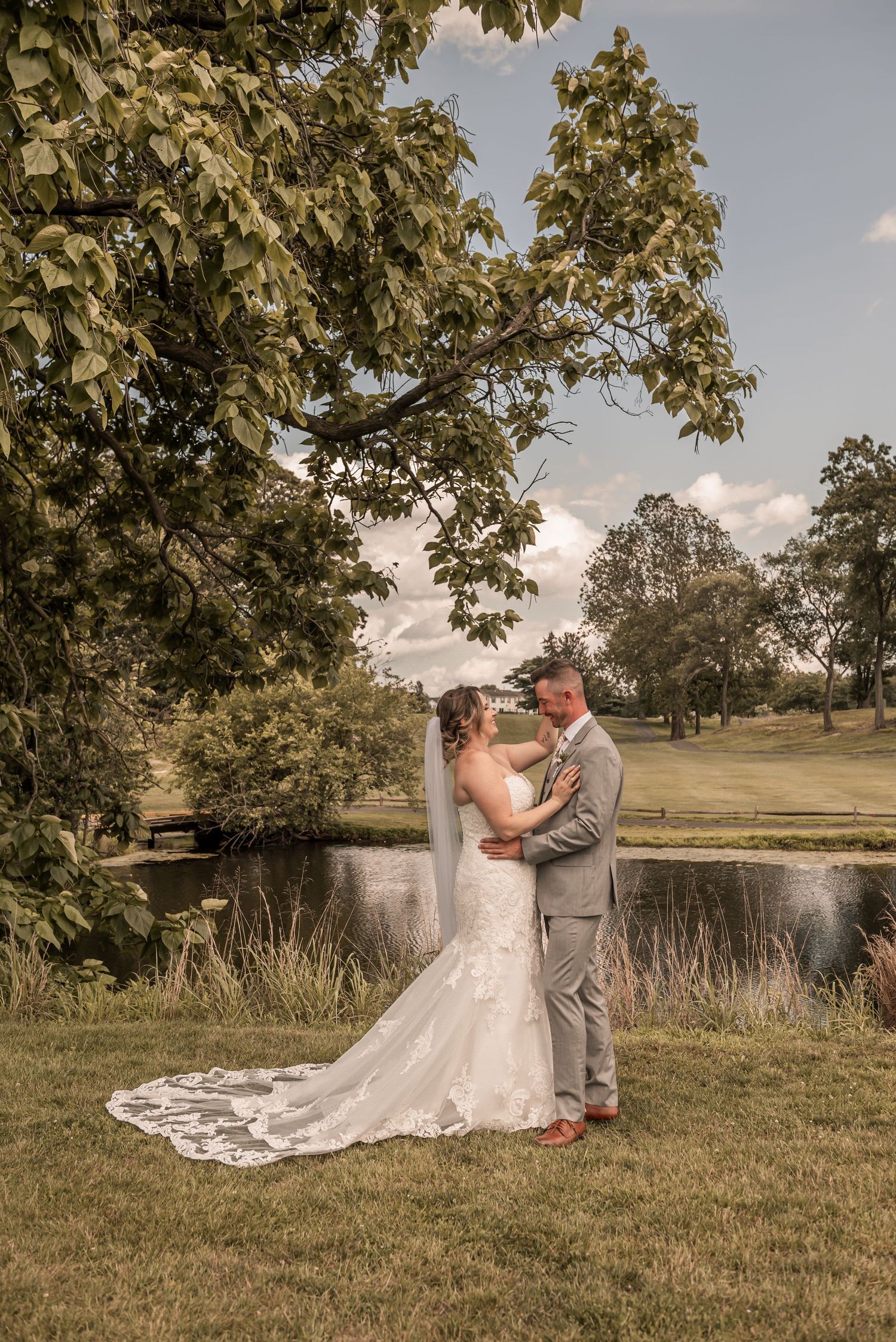 A bride and groom share an intimate first look moment by a serene pond on their wedding day.