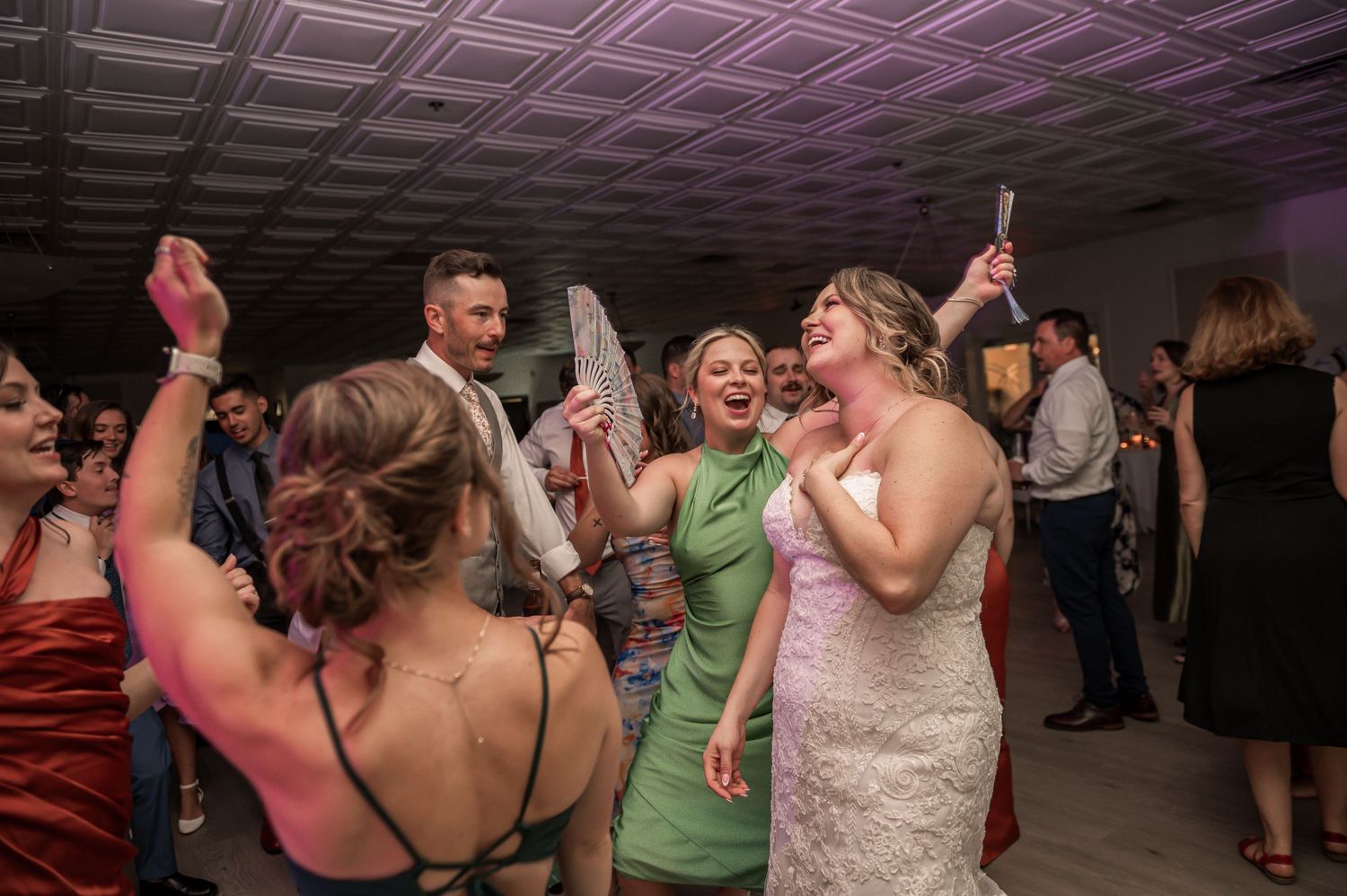 Wedding guests dancing and celebrating on the dance floor during a lively reception party.