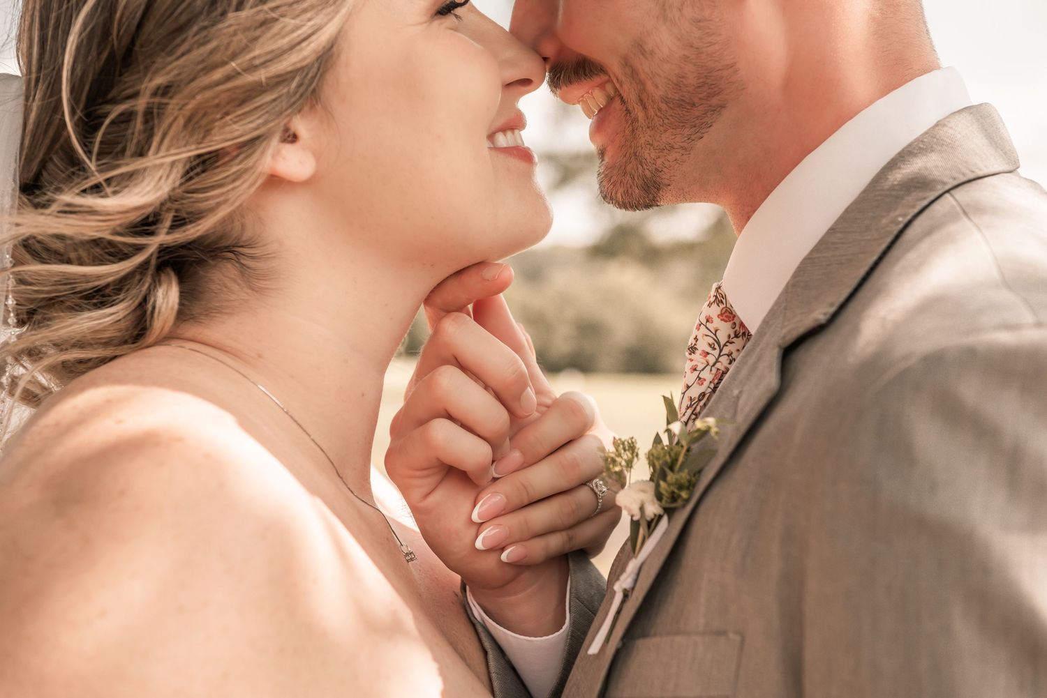 A bride and groom share a tender moment, holding hands and smiling at each other on their wedding day.