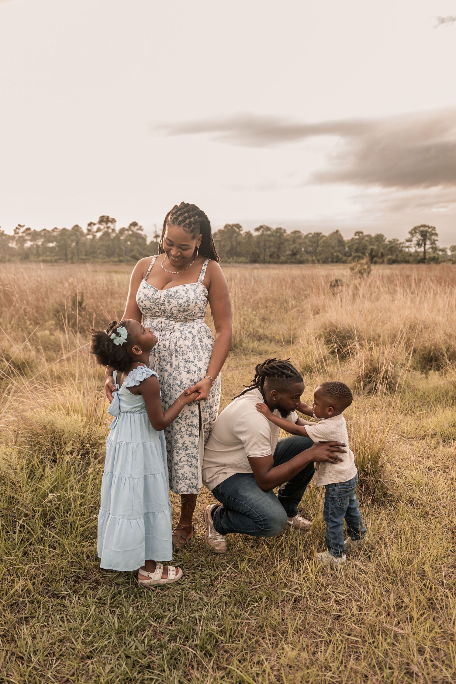 Family shares tender moments together in a golden field during sunset, creating heartwarming outdoor portraits.