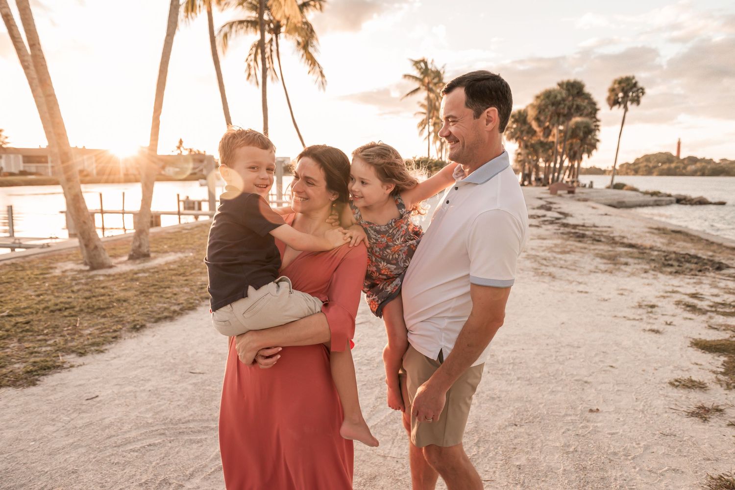 Family enjoying sunset on a beach with palm trees and golden light creating a warm, tropical atmosphere.