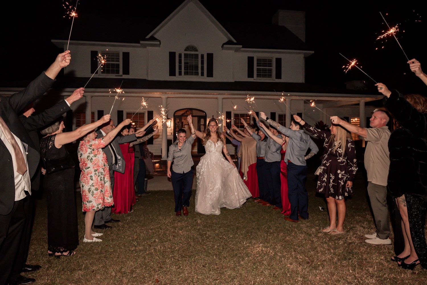 Wedding guests form a sparkler tunnel at night creating a magical exit pathway for the newlyweds.