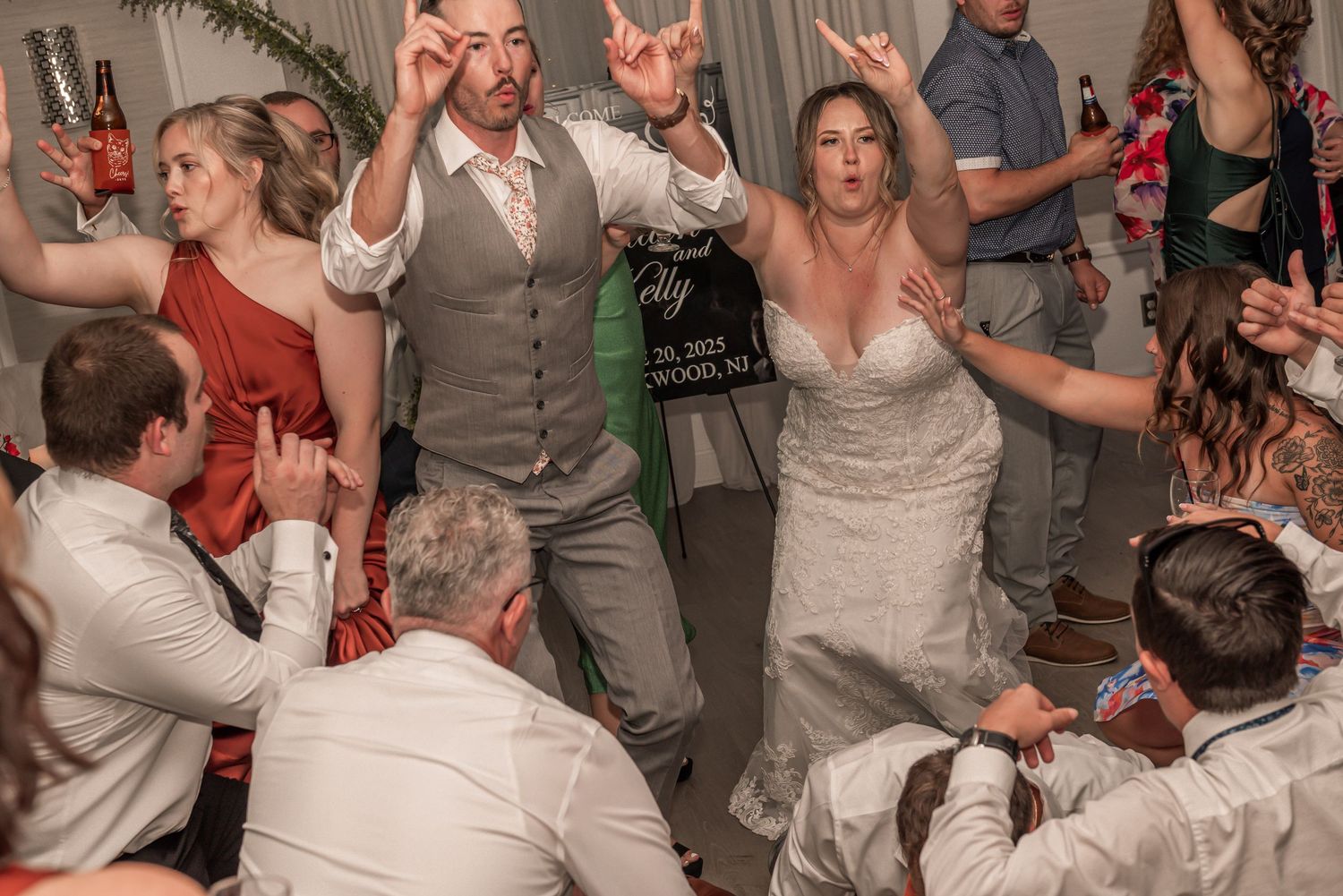 A lively wedding reception dance floor shows guests celebrating and dancing together in formal attire.