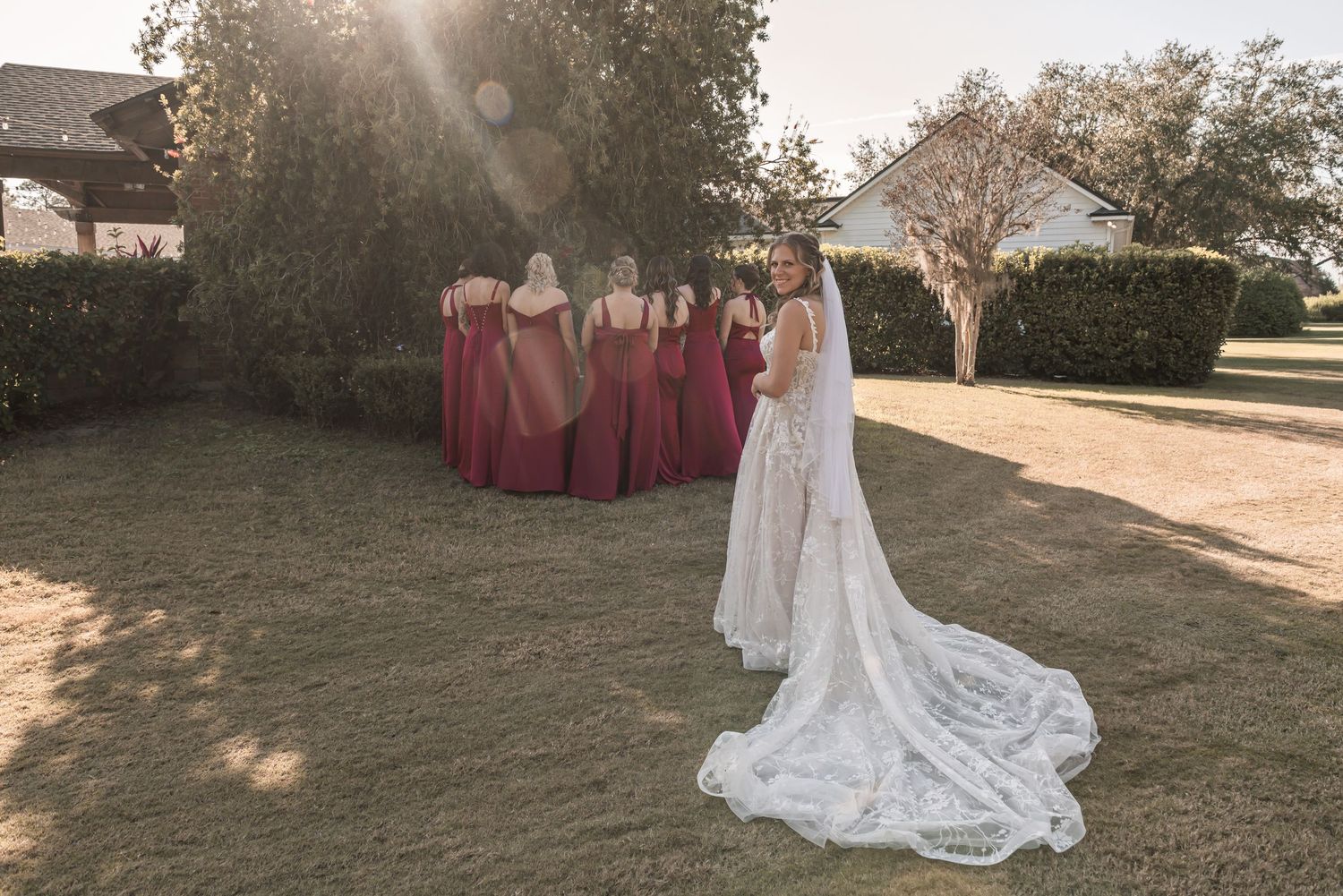 A stunning outdoor wedding scene with flowing white gowns and bridesmaids in pink dresses at golden hour.