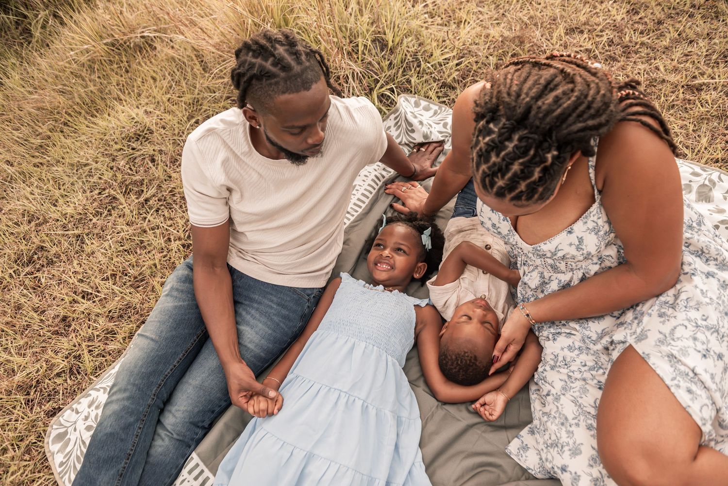 A series of intimate outdoor family portraits showing tender moments between parents and children on dry grass.