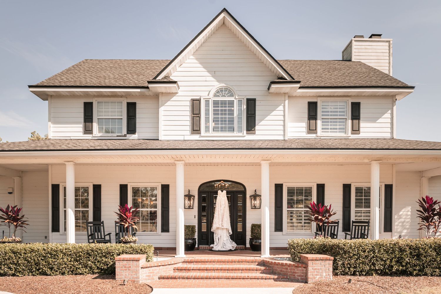 A series of exterior views of a luxurious white single-story ranch home with manicured landscaping and covered porches.
