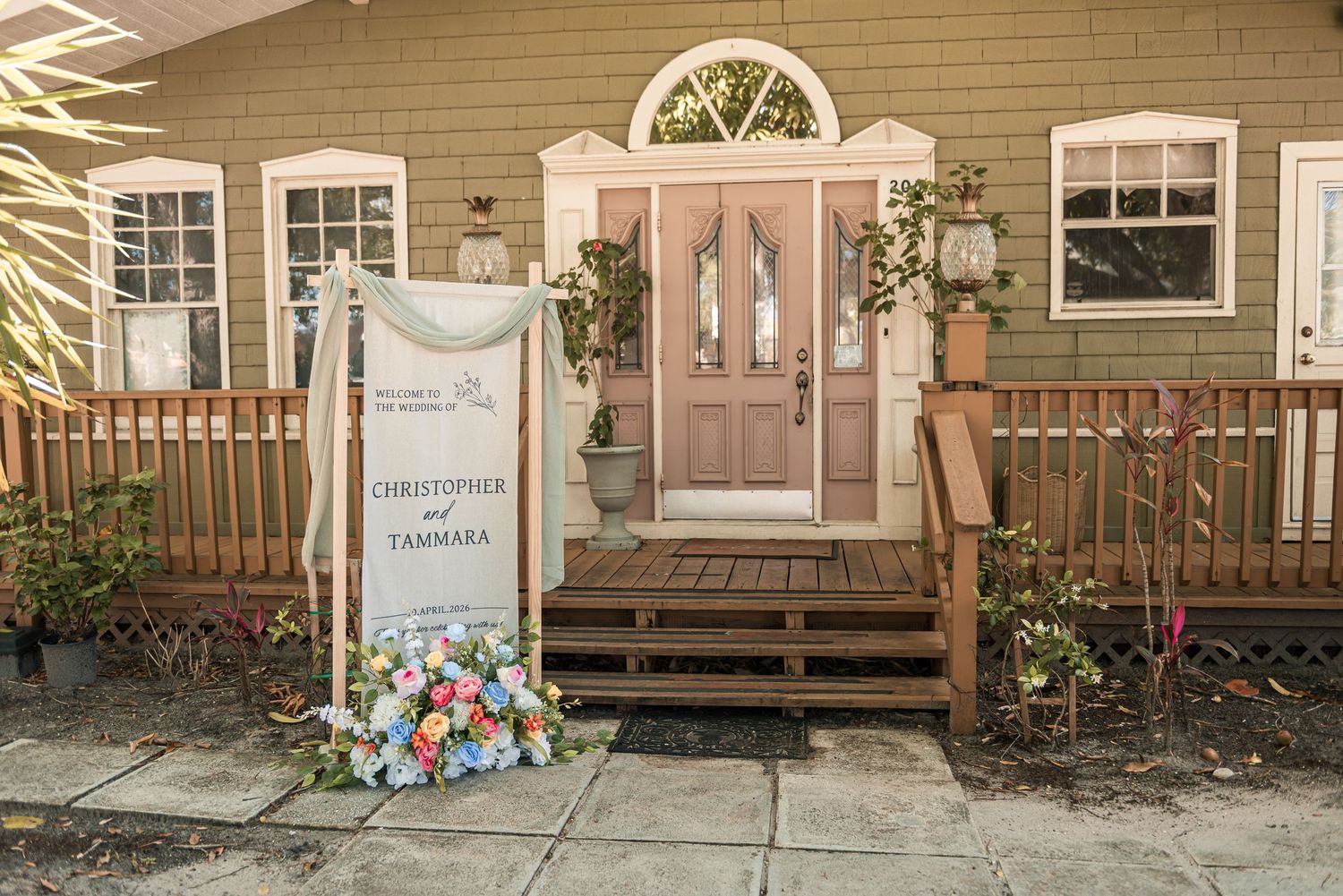 Charming wedding entrance sign for Christopher and Tammara with floral arrangement outside a green house.