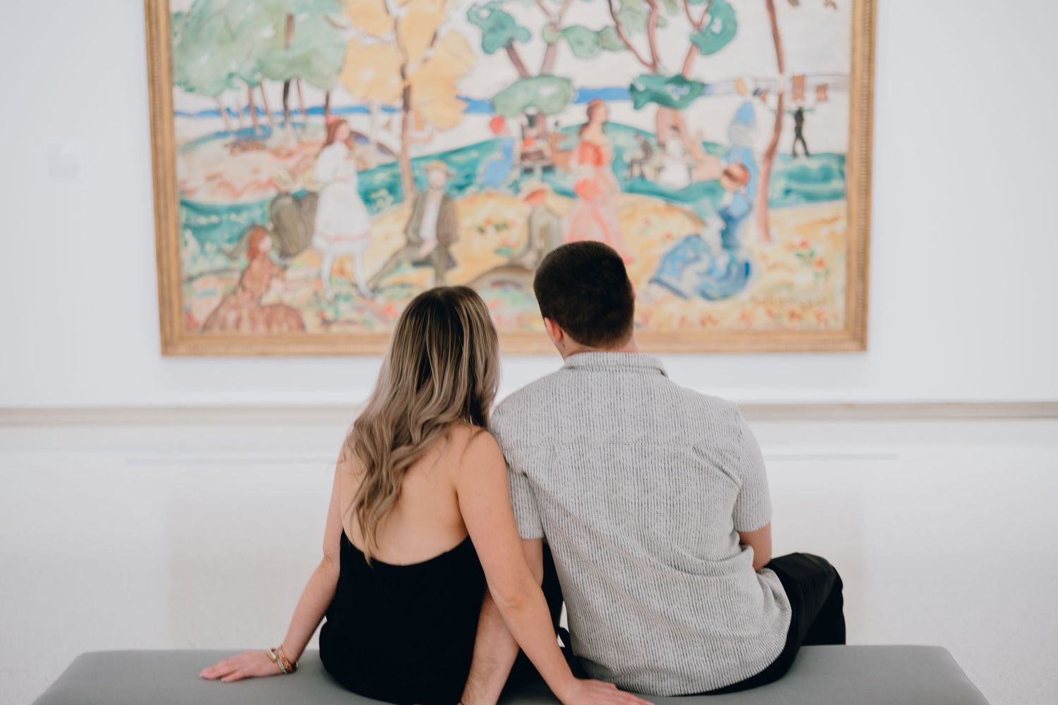 Couple viewing colorful artwork together in gallery setting.
