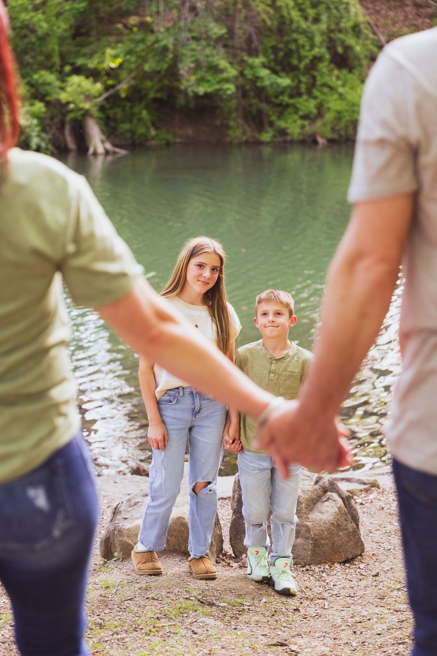 Family enjoying a nature walk together on a trail by a serene lake on a sunny day.