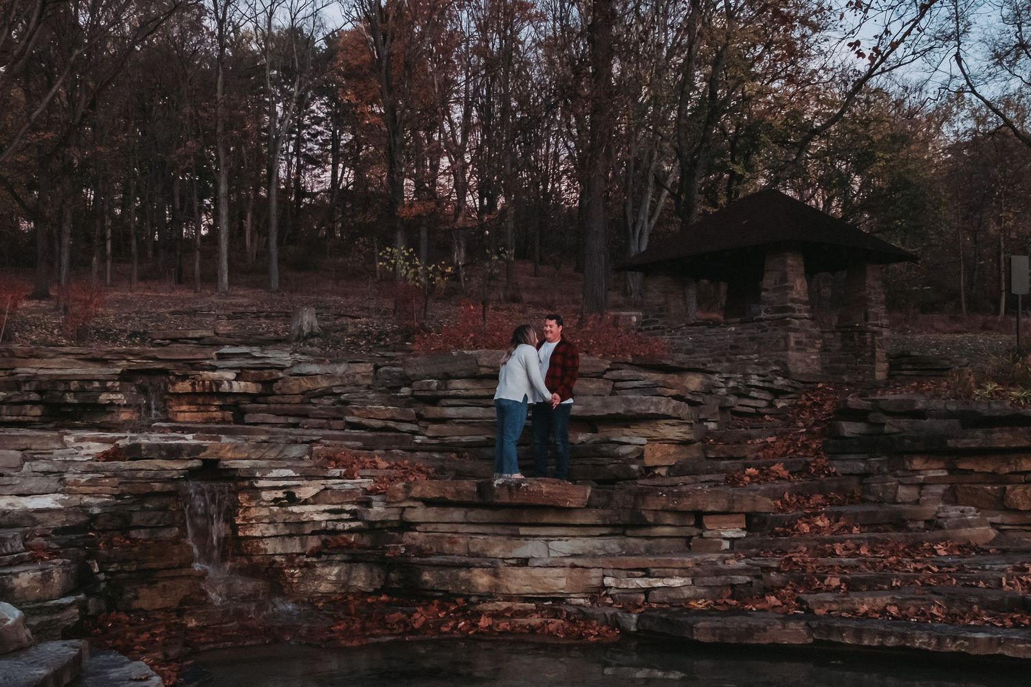 A romantic autumn photoshoot at a rustic stone wall in the woods.