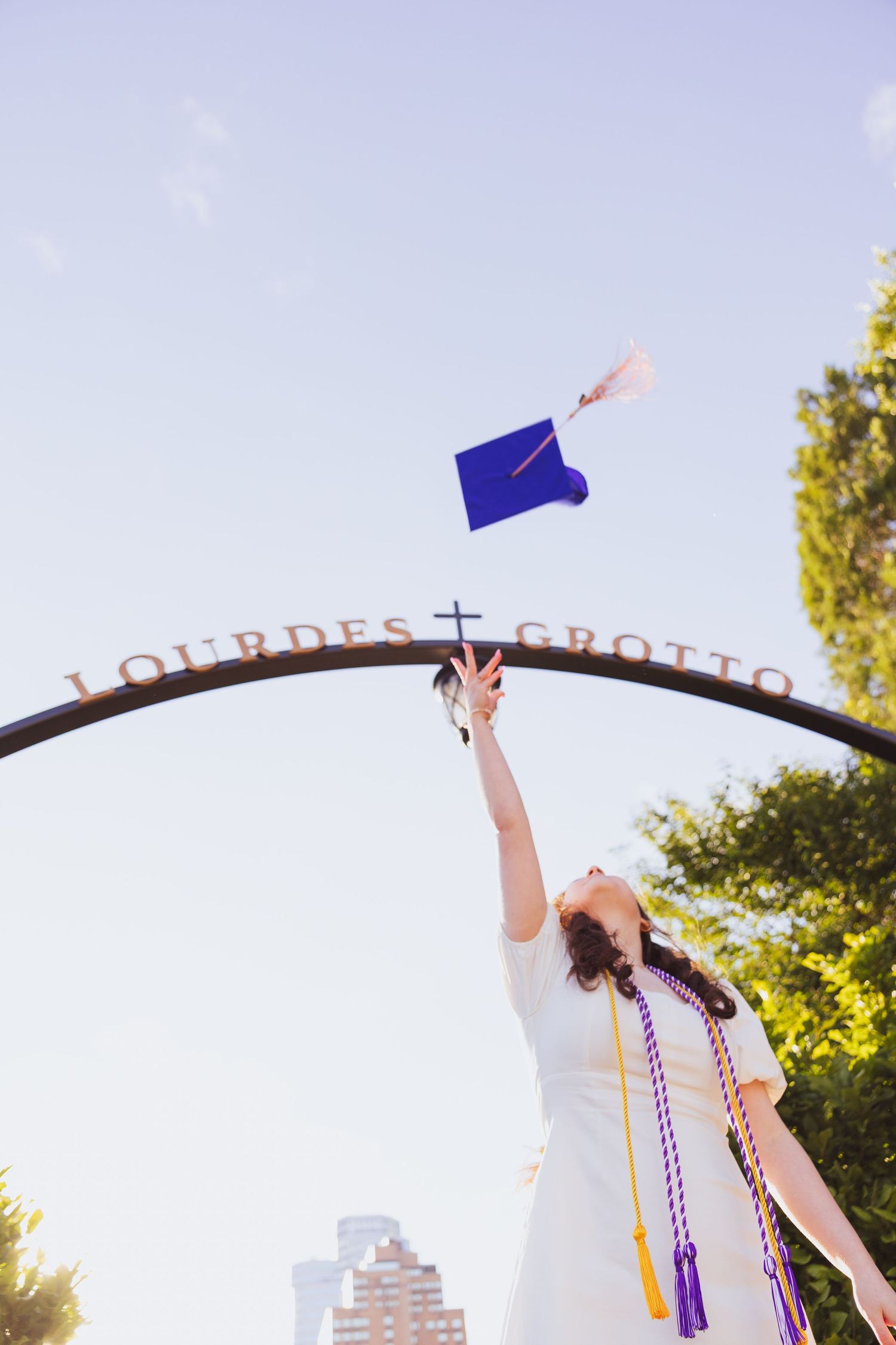 Person wearing blue dress reaches upward catching purple paper airplanes against golden sunset sky in park setting.
