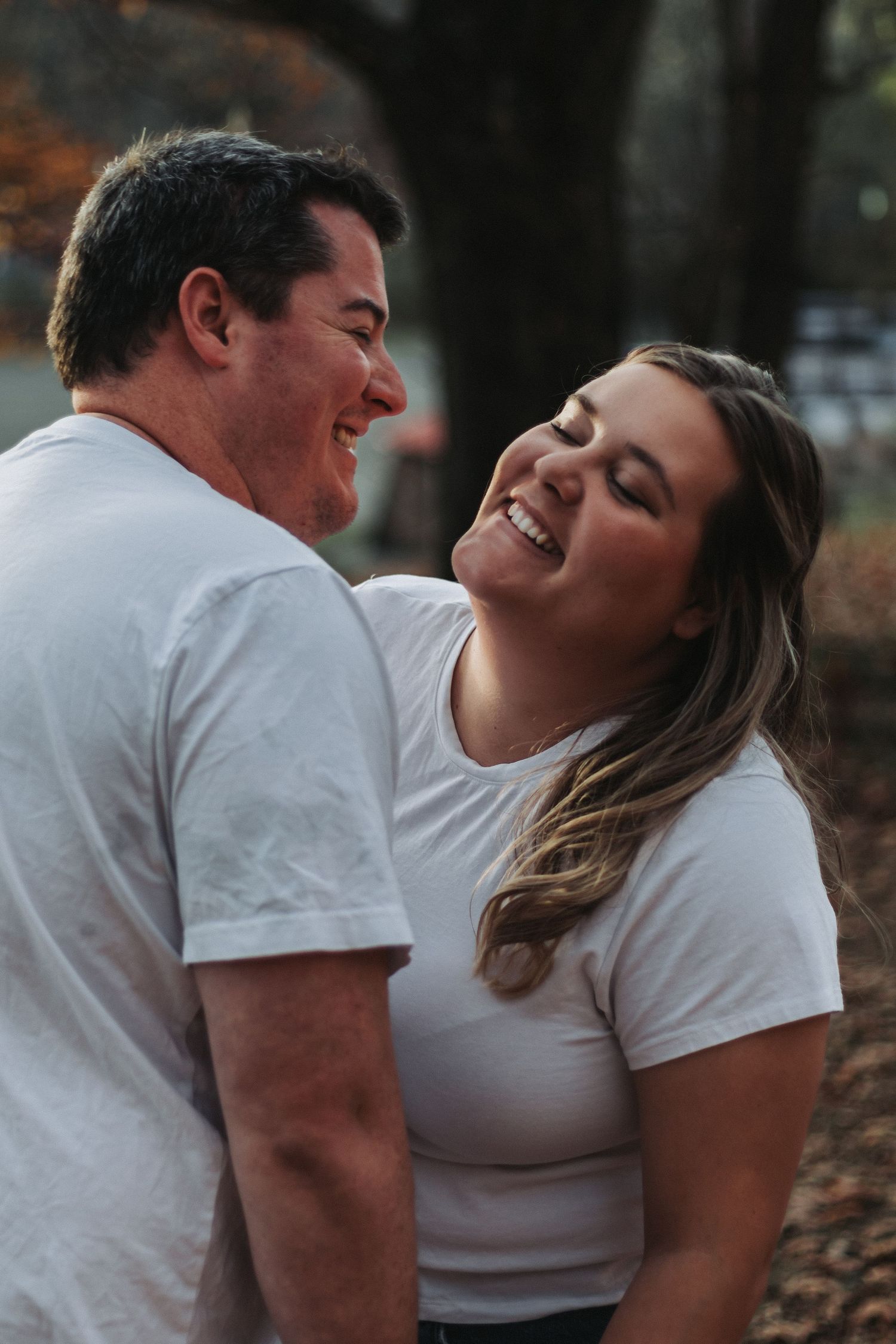 A candid moment between a couple wearing white t-shirts during a fall photoshoot.