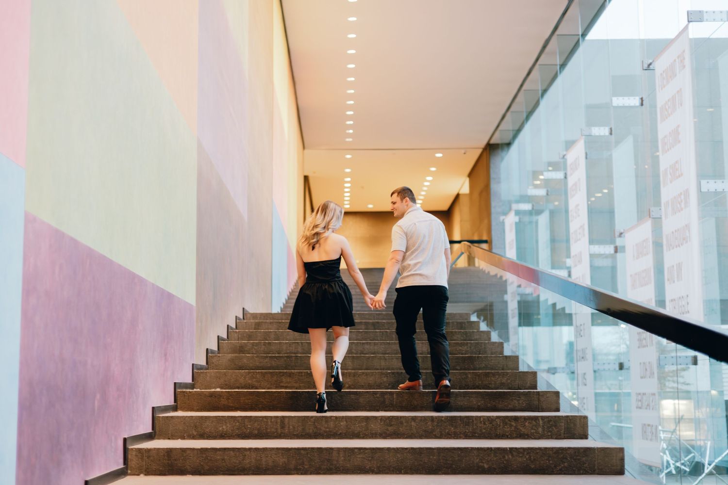 Couple walking up modern staircase together holding hands.