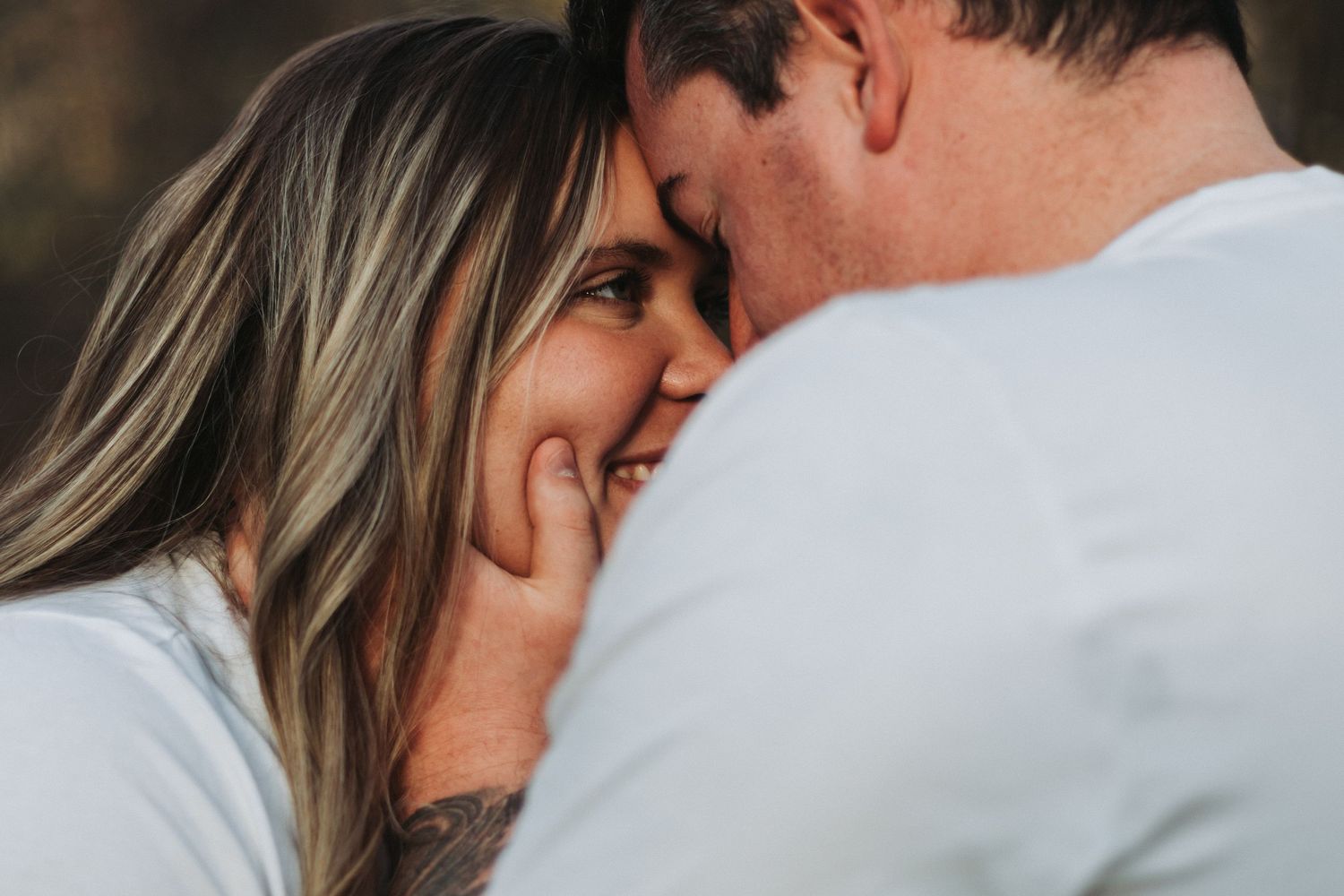Close-up portrait of a couple sharing an intimate romantic moment in warm lighting.
