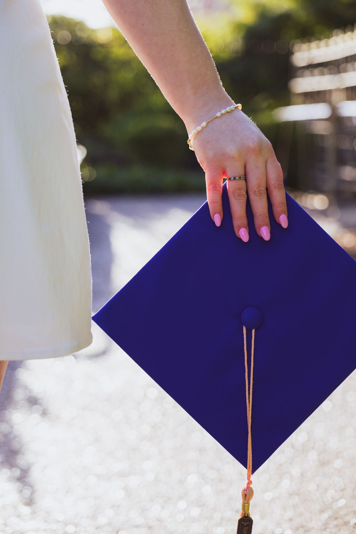 Hands lowering navy blue graduation caps onto white folded graduation gowns in multiple stepped shots.