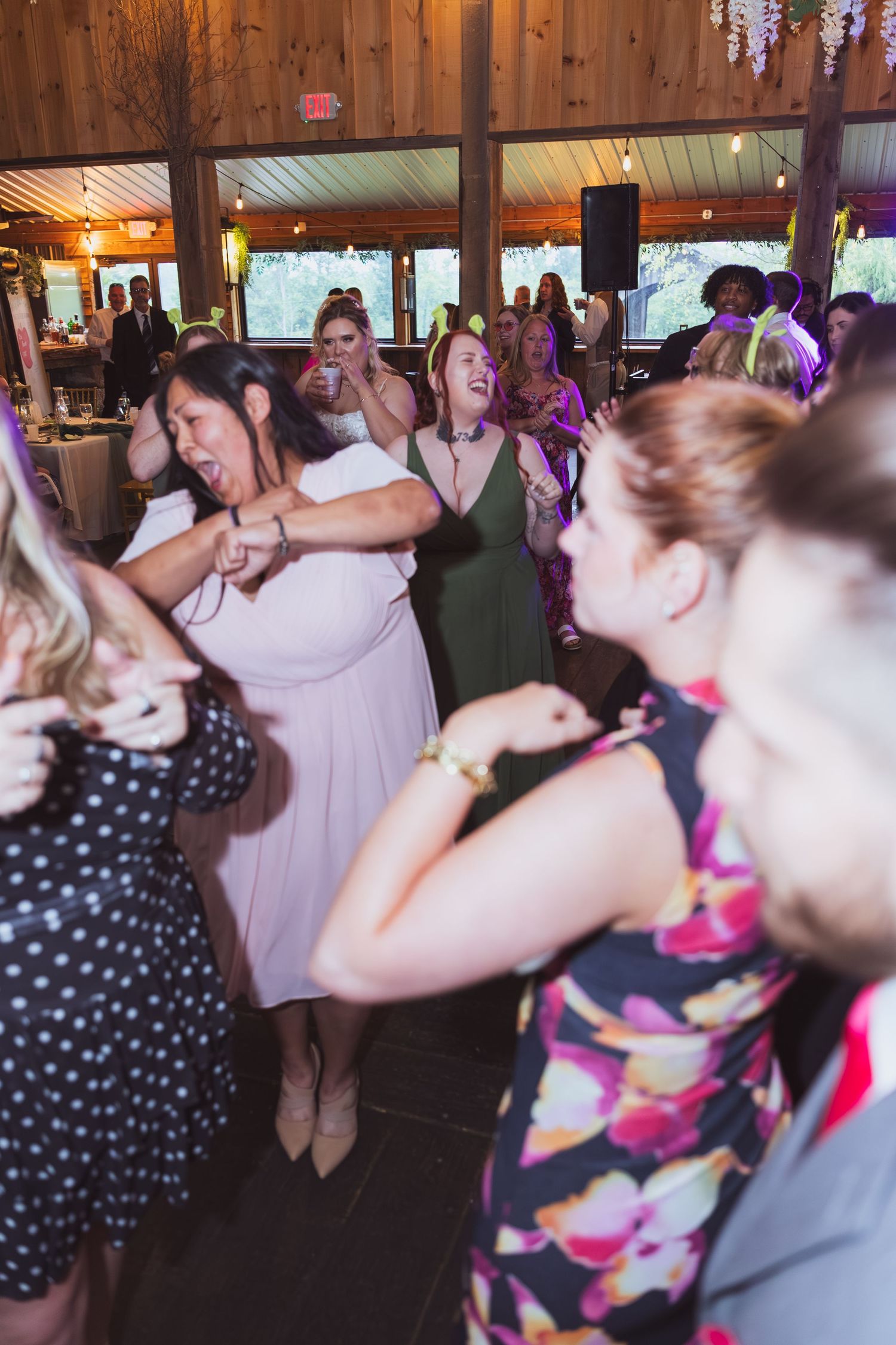Women dancing joyfully together at a lively rustic barn wedding reception celebration.