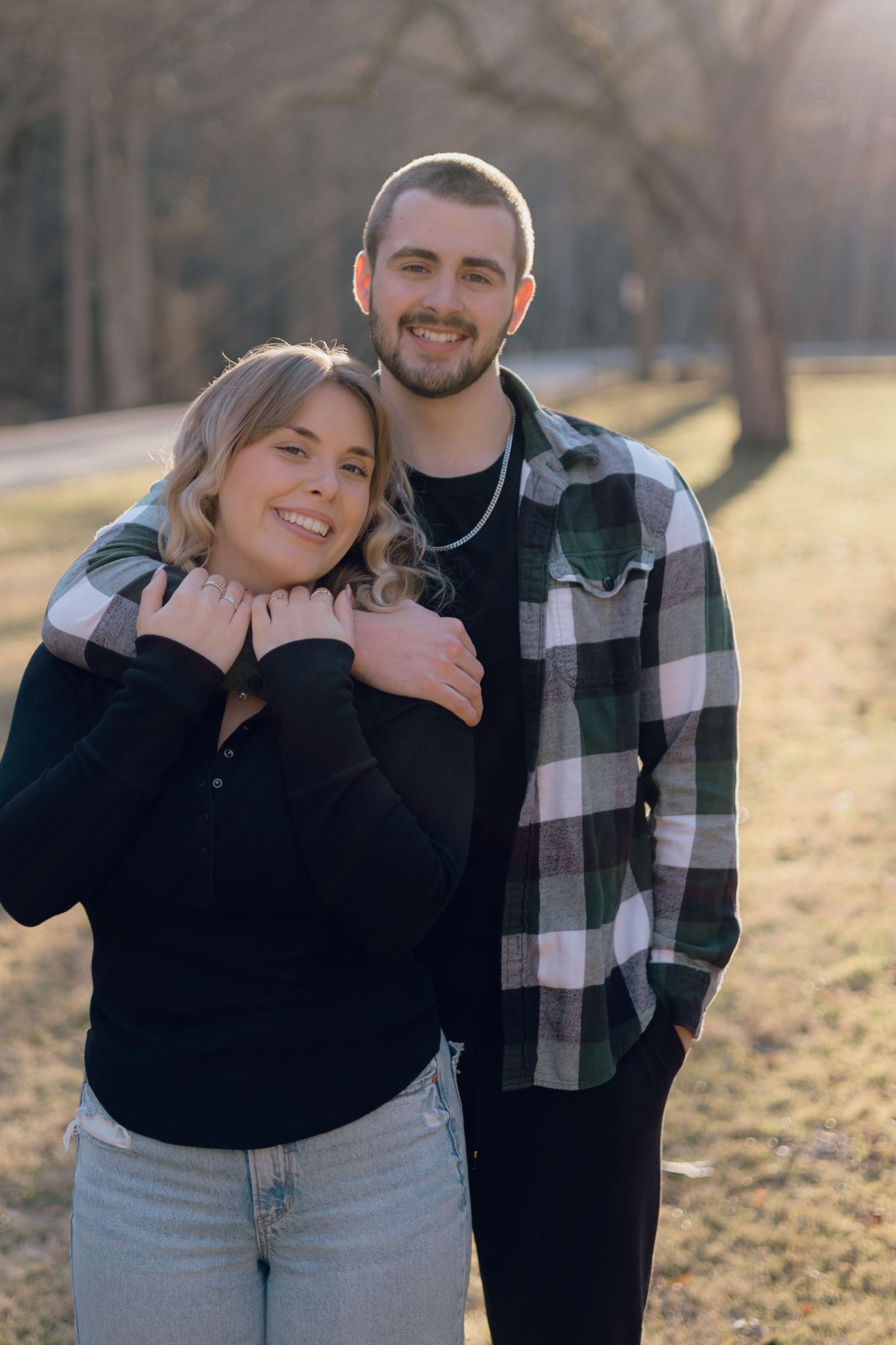 Happy couple posing together outdoors in casual wear during sunset.