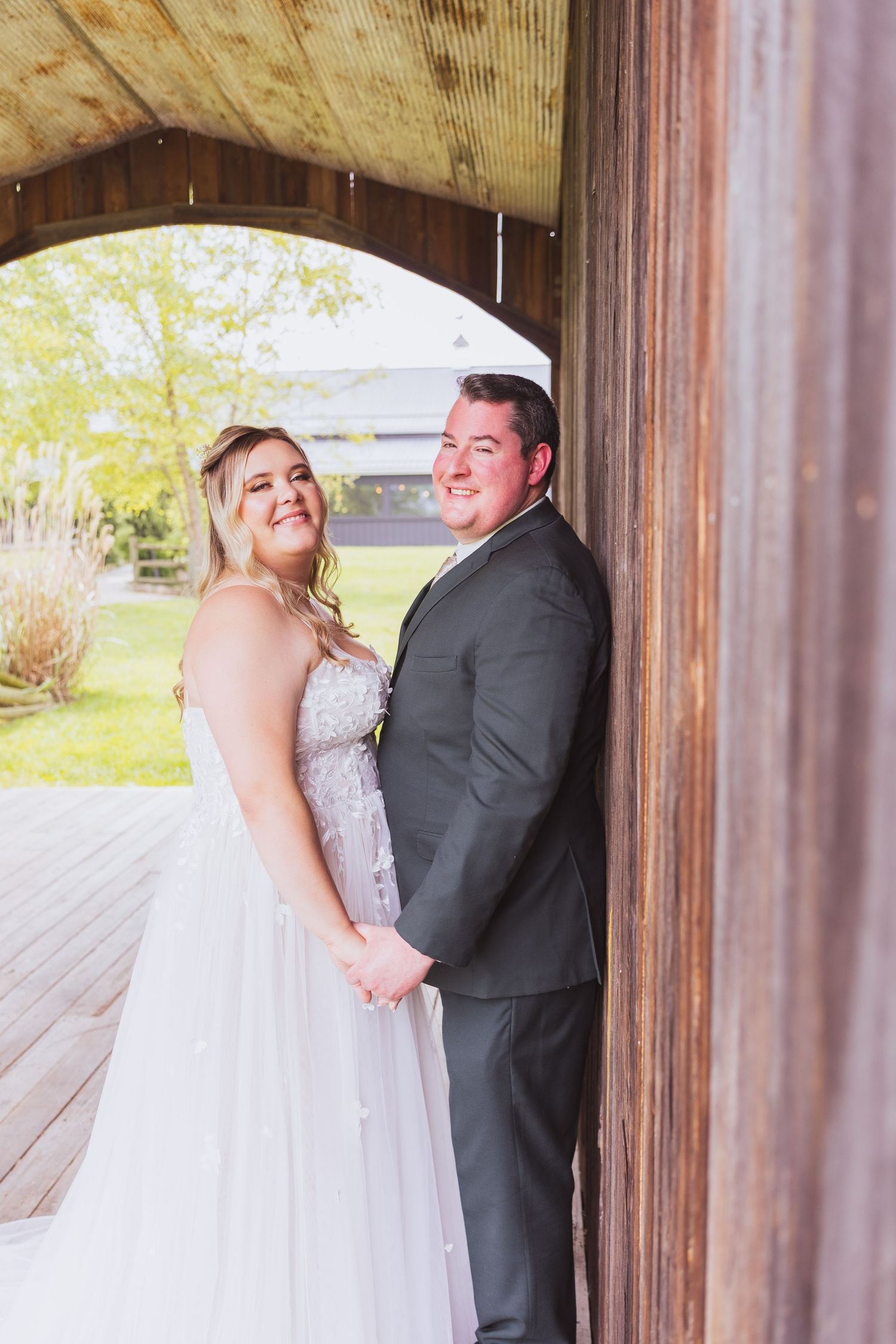Wedding couple embracing in rustic wooden barn with natural light streaming through.