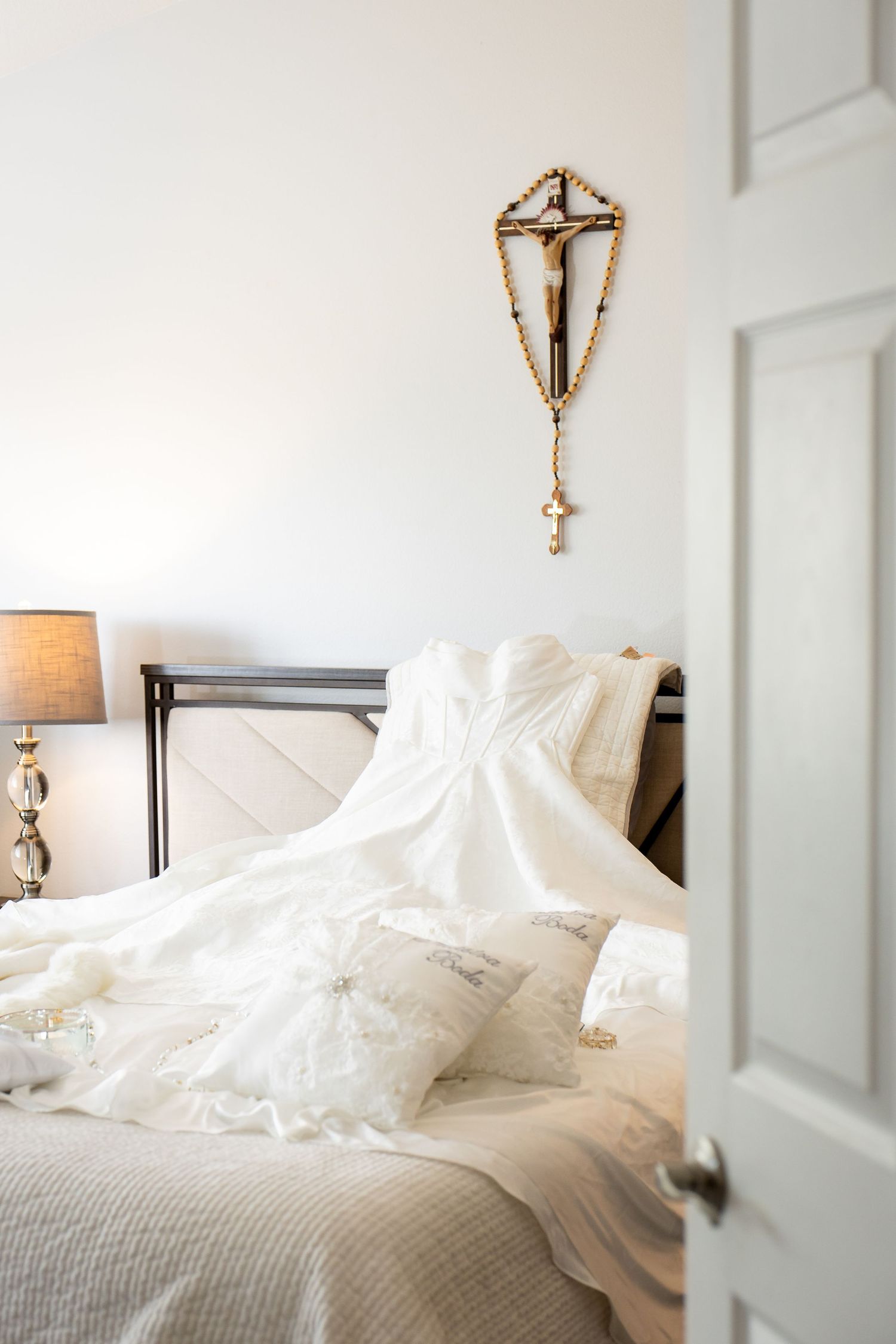 White bedding and linens in a bright, elegant bedroom with wall sconces and soft lighting.