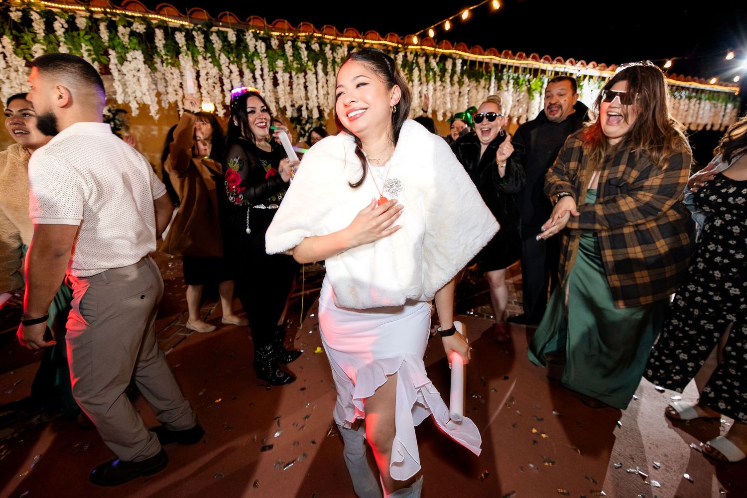 Couples dance together at a rustic barn wedding reception under string lights and wooden beams.