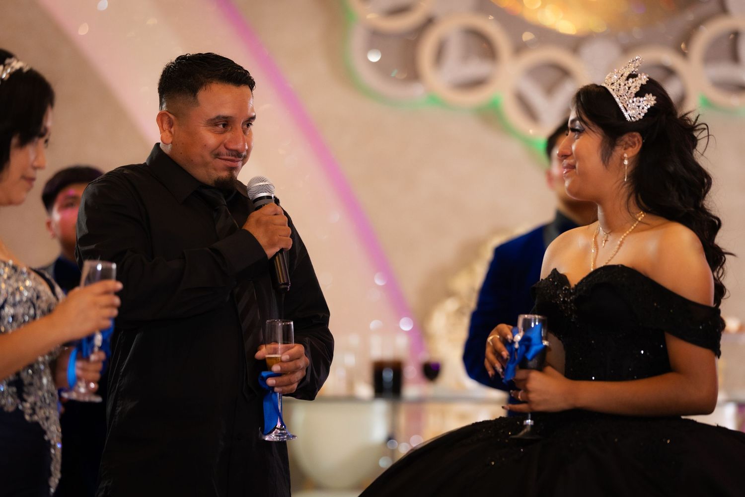 Couples dance together at an elegant reception with soft pink lighting and decorative elements in the background.