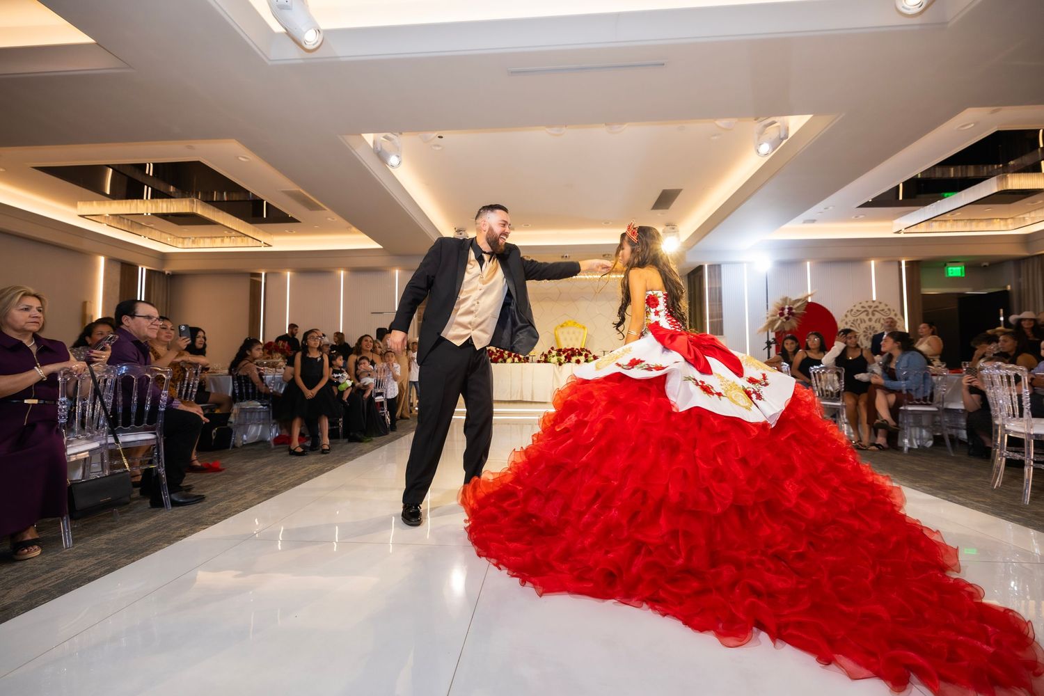 People dancing and celebrating in a bright indoor venue with a flowing red dress taking center stage.