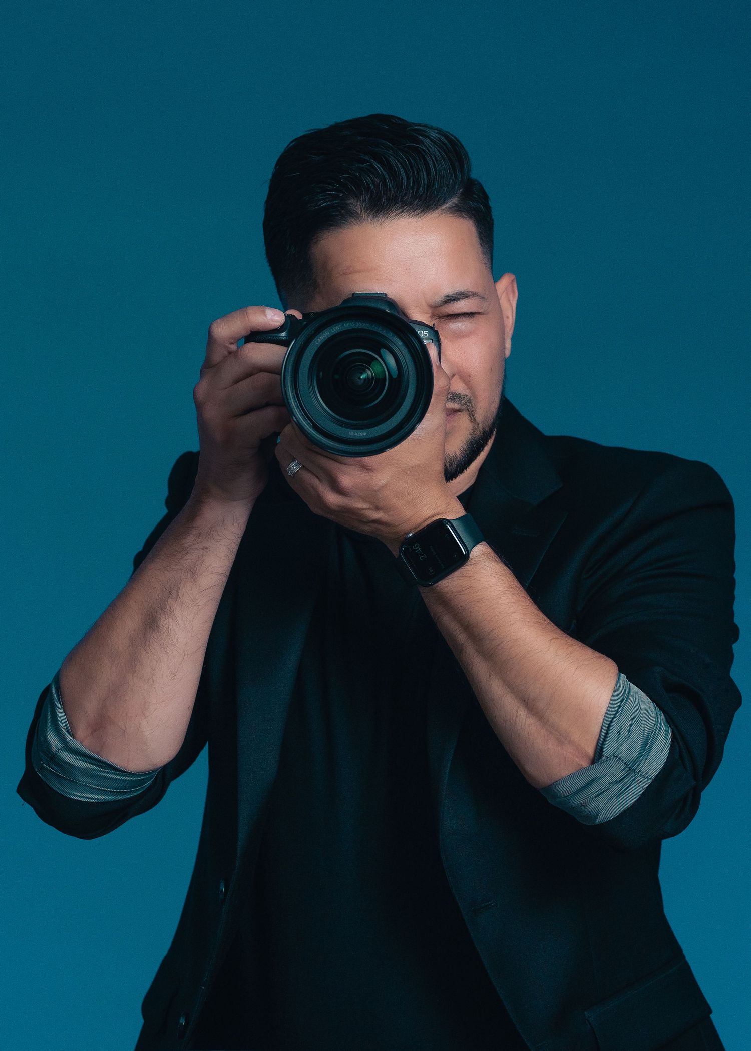 Professional photographer taking picture with DSLR camera against blue background.