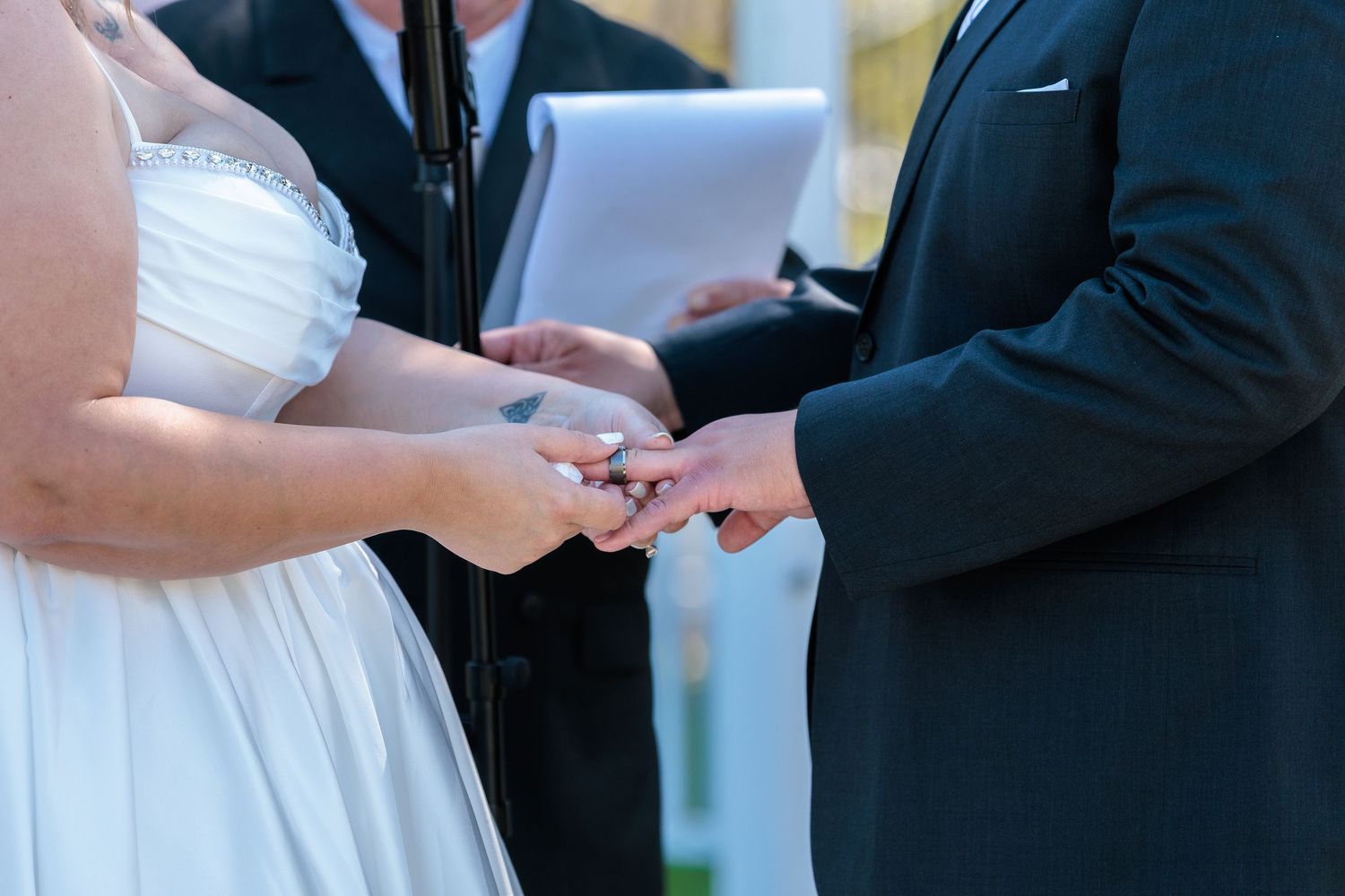Wedding ceremony participants exchange rings during an intimate indoor ceremony.