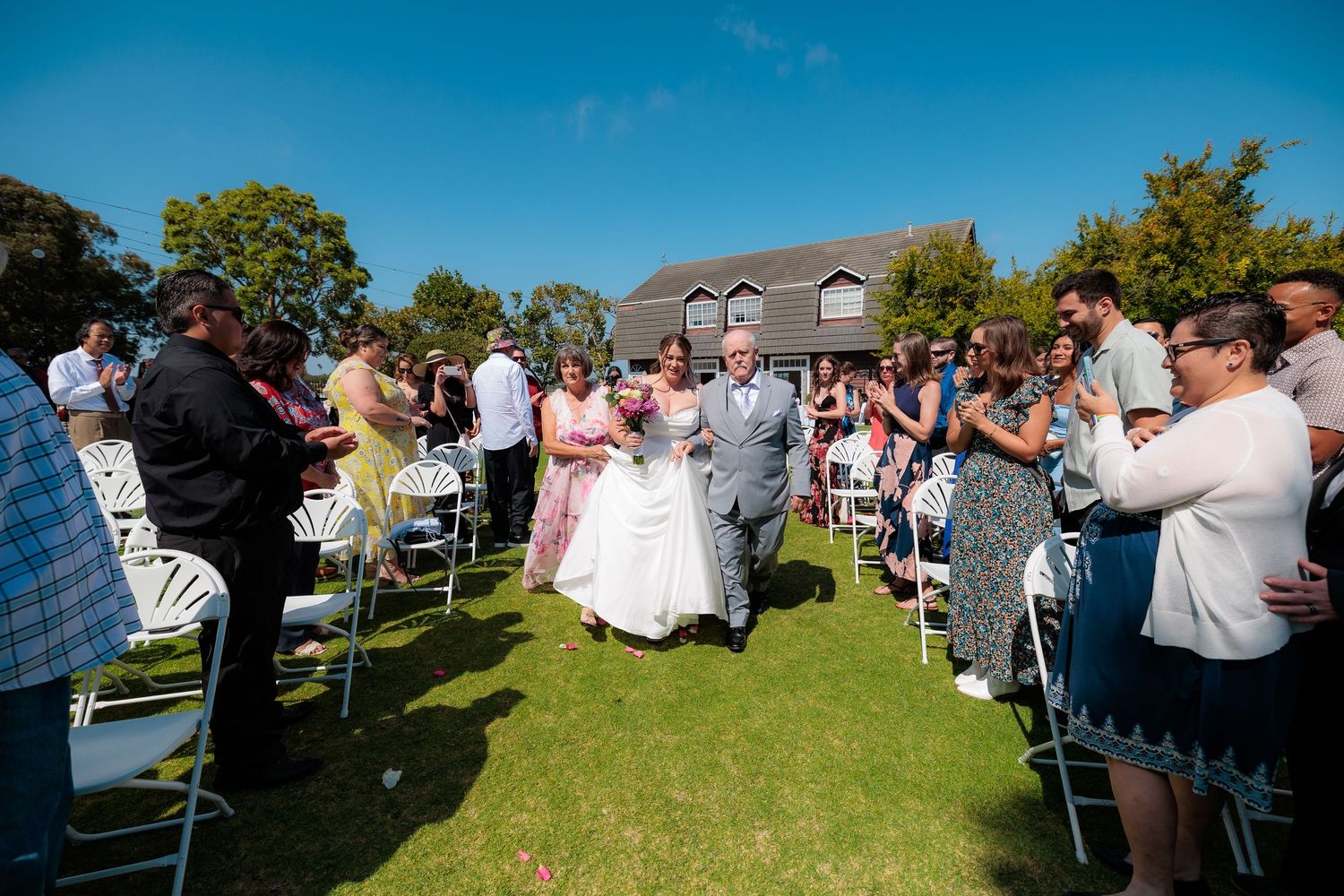 Panoramic sequence of an outdoor wedding ceremony on a sunny day with guests seated on a grassy lawn.