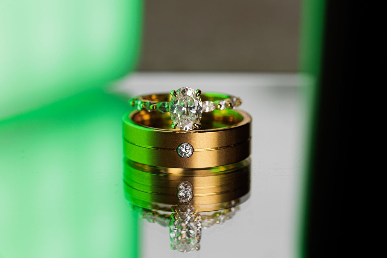 Wedding rings with floral details sparkle against a green-tinted background.