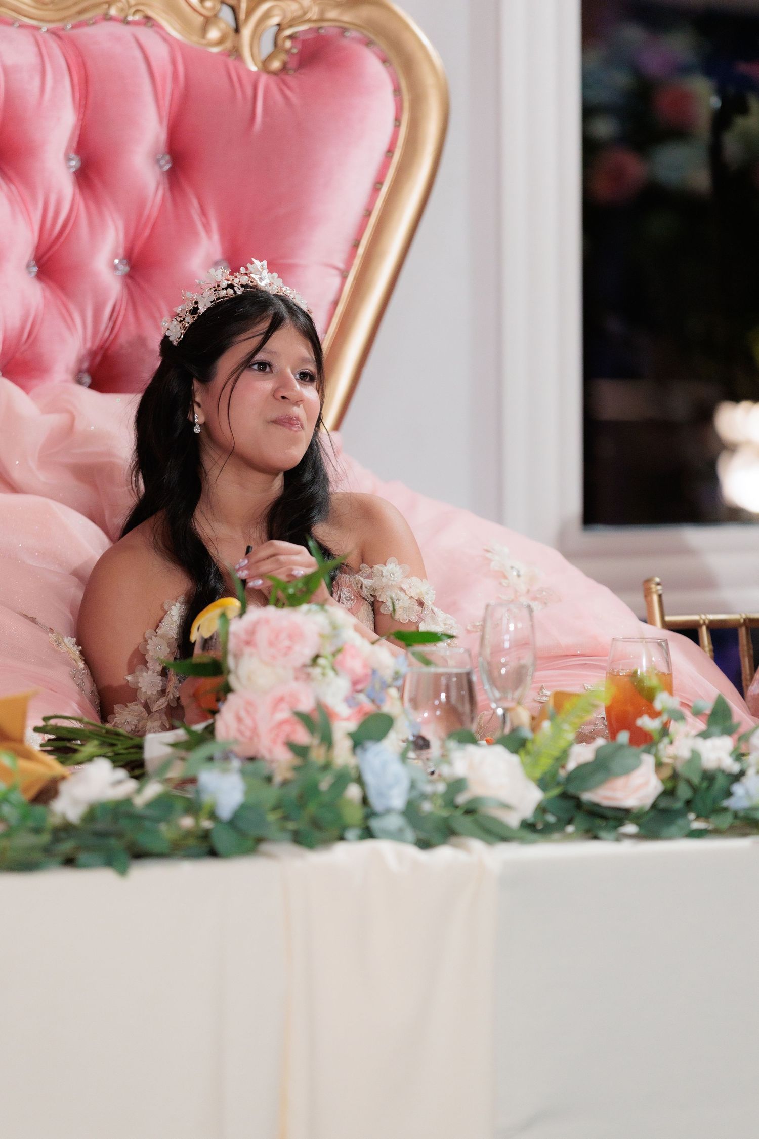 Elegant pink tufted chair and floral table decorations at a formal event reception.