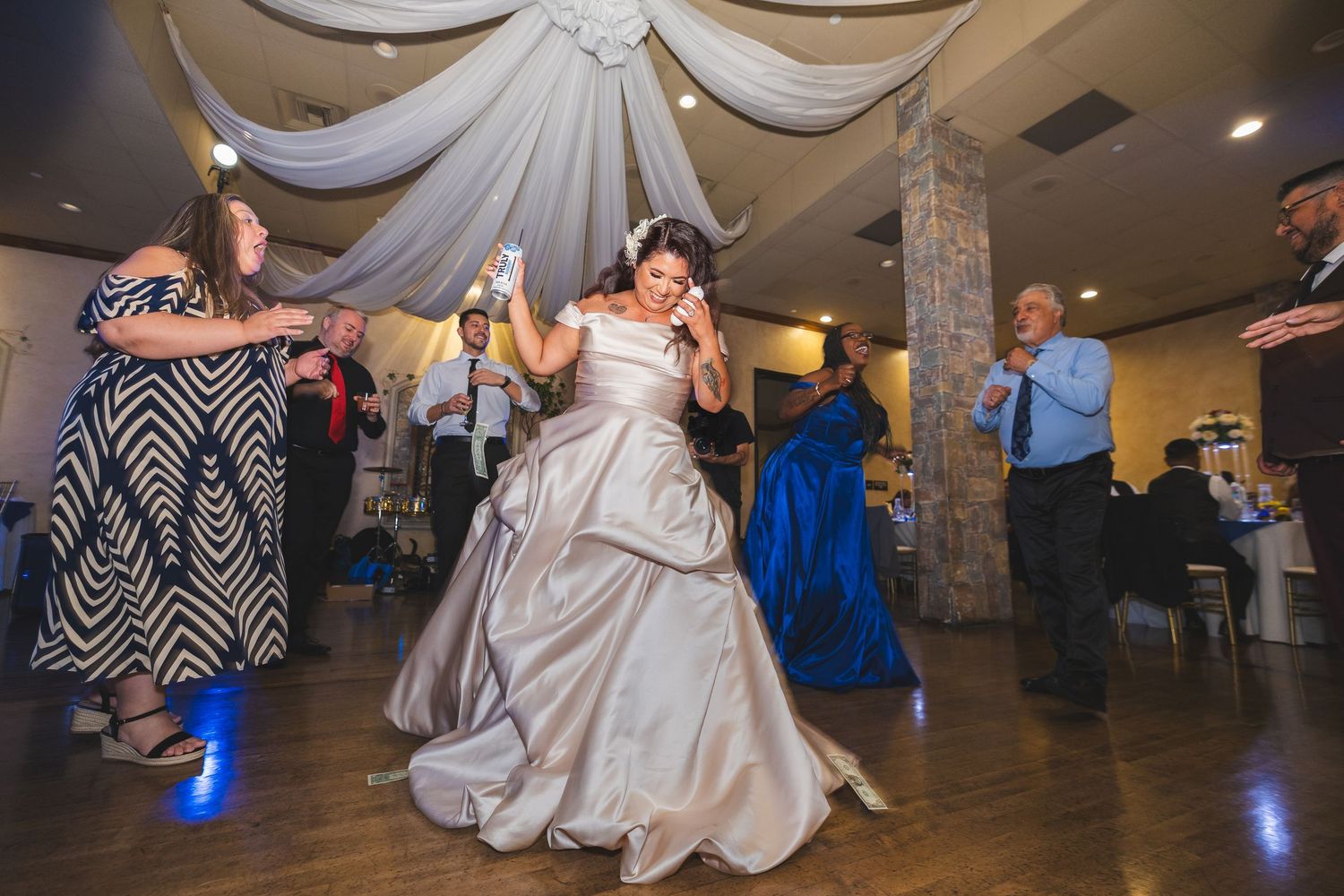Wedding couple and guests dance and celebrate on a ballroom floor during a reception party.