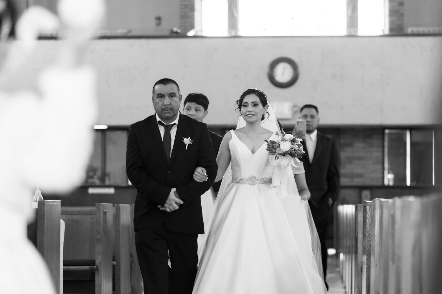 A black and white photo of a wedding ceremony in a church with people standing at the altar.