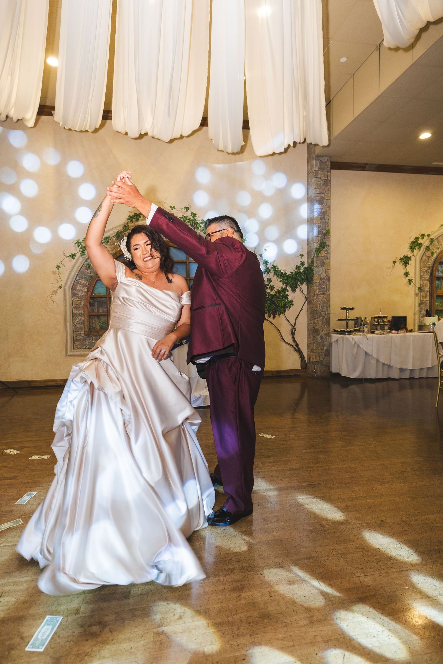 A couple dances at their wedding reception with twinkle lights and white drapes in the background.