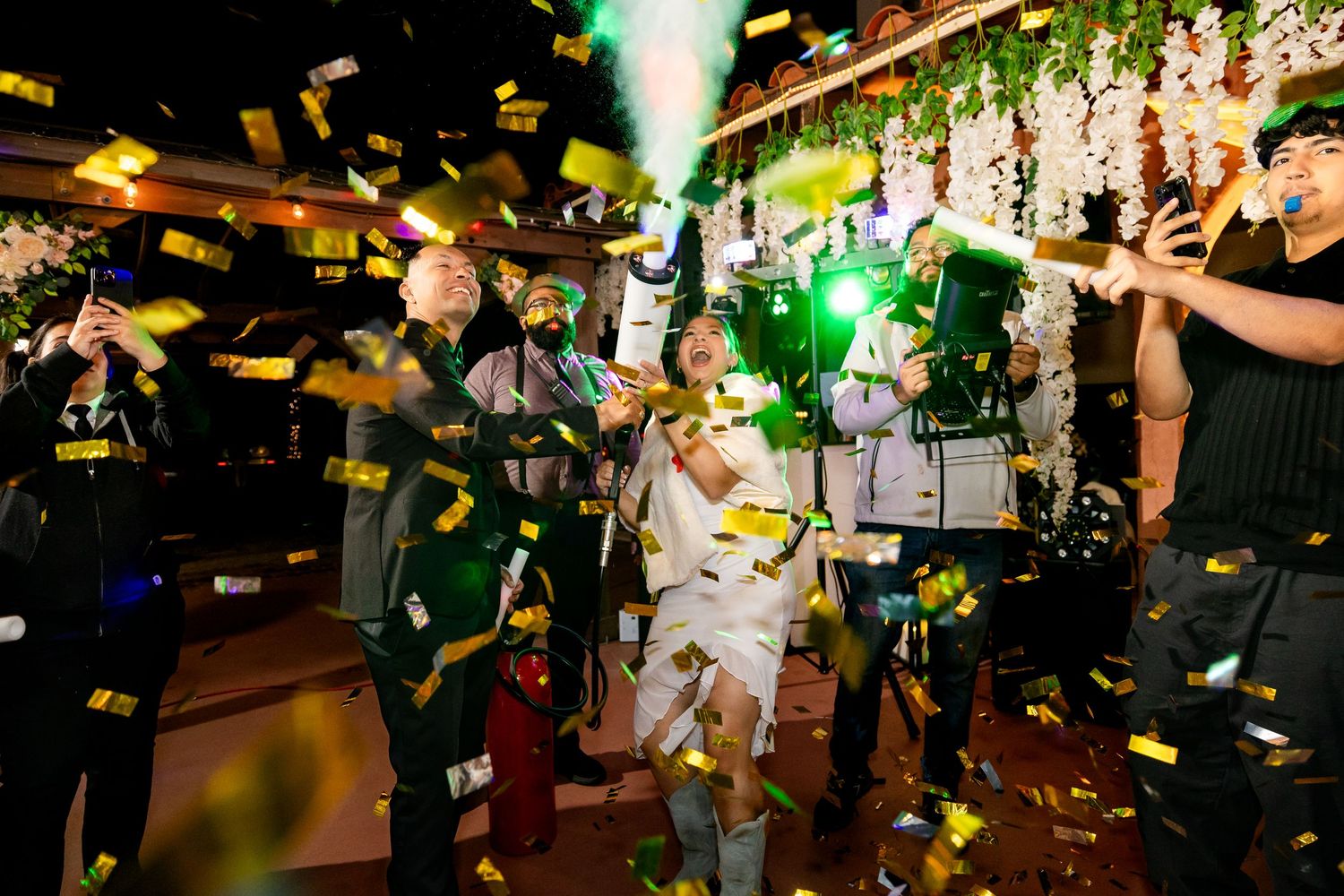 Confetti and green lights fill a nightclub as partygoers celebrate on a crowded dance floor during an event.