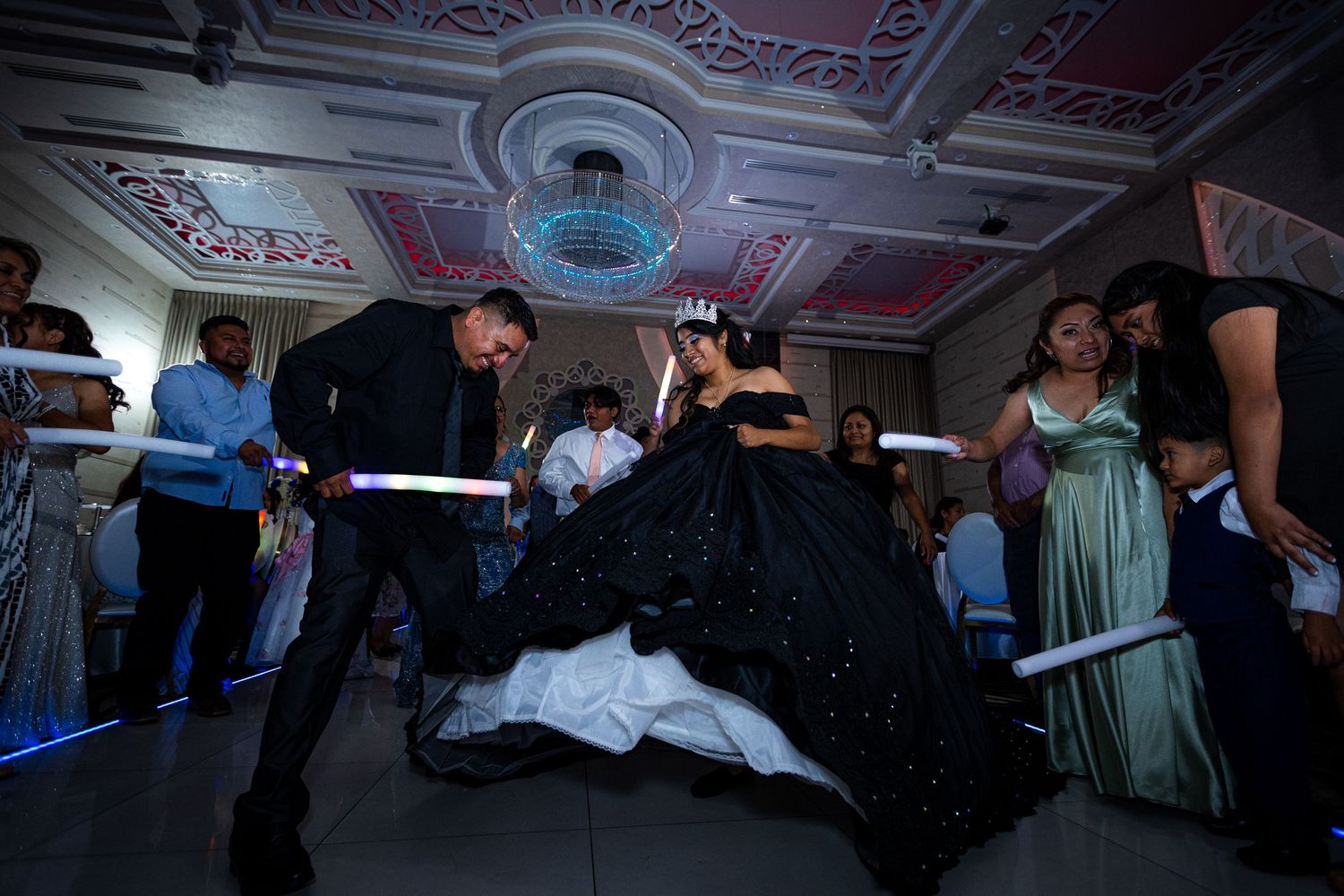 Dancers perform an elegant ballroom dance move with dramatic flair at an ornate venue with decorative ceiling details.