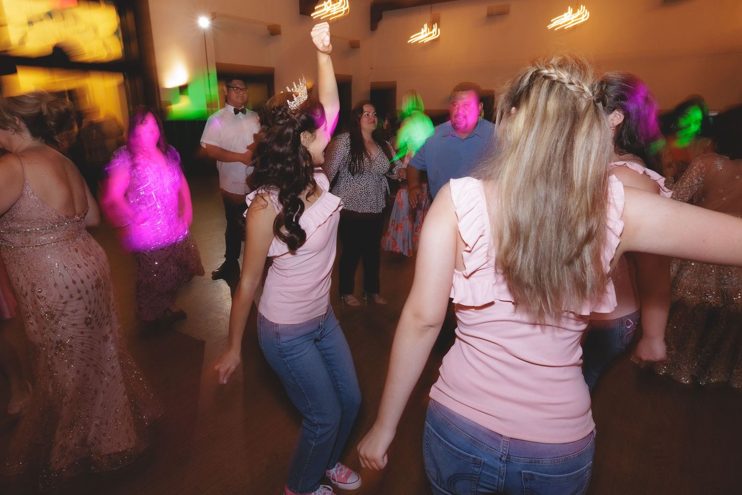 People dancing and socializing at a party venue with colorful lighting and festive atmosphere.