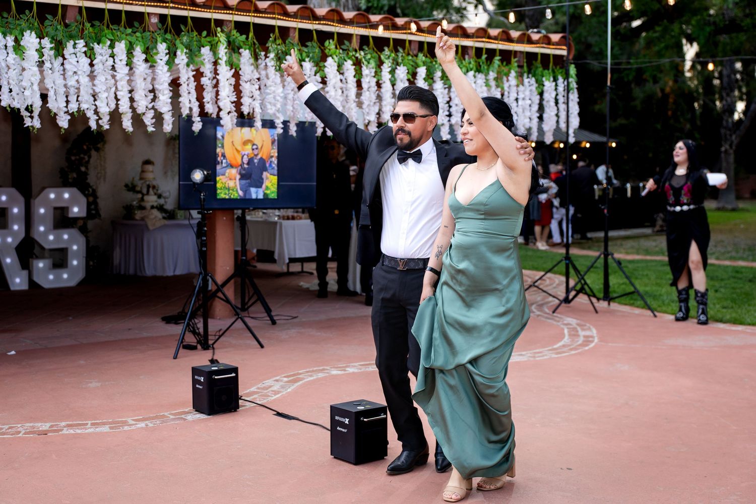 A couple dancing at an outdoor event with white streamers and decorative lights hanging overhead.