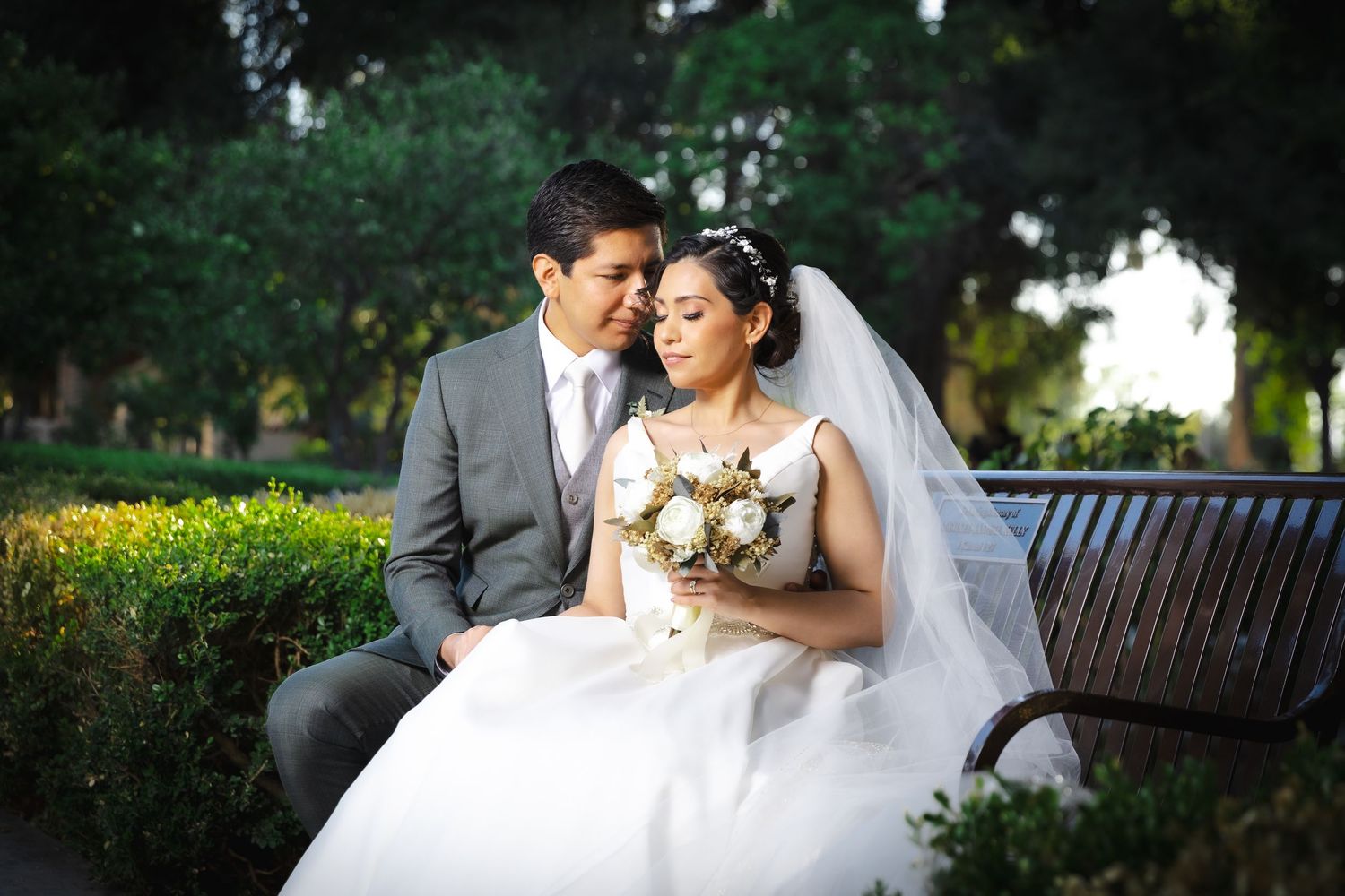 A romantic wedding couple embraces in a lush garden setting with natural lighting and floral arrangements.