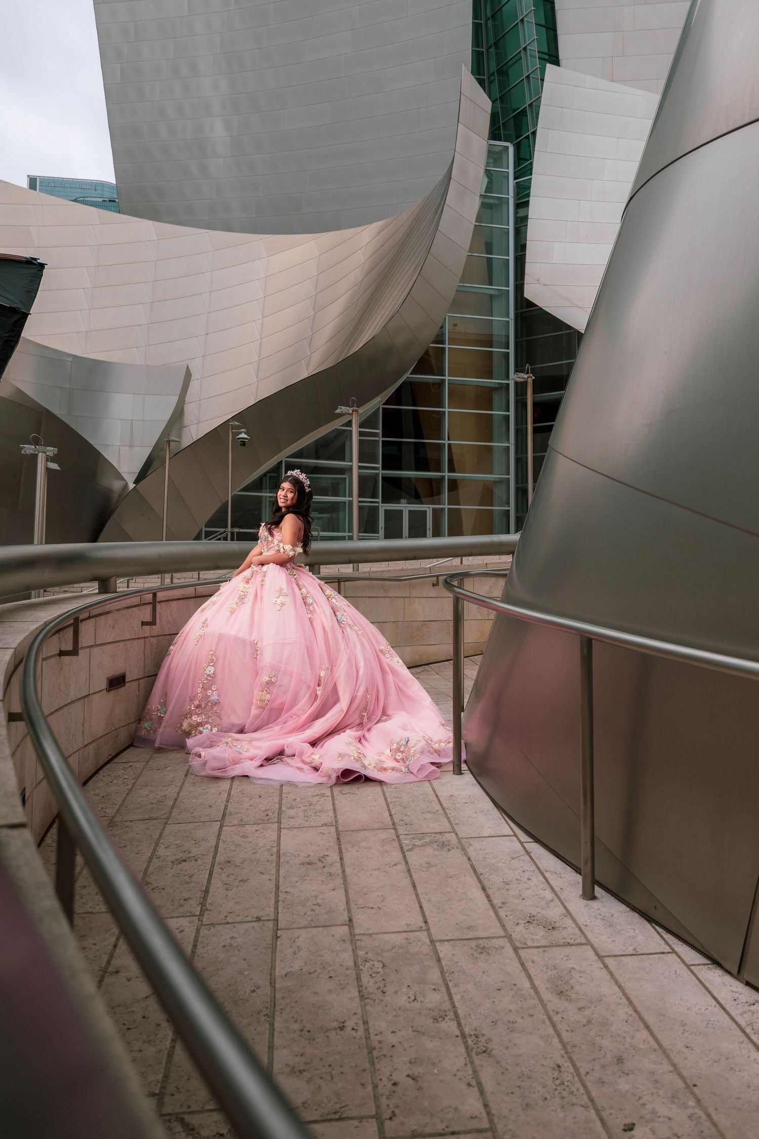 A pink ball gown flows elegantly against the modern architecture of the Walt Disney Concert Hall in Los Angeles.