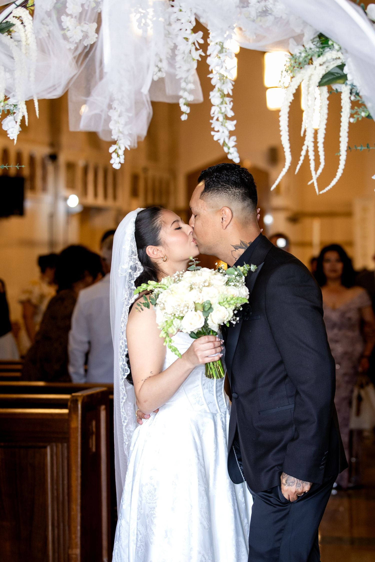 A bride and groom share romantic kisses during their wedding ceremony in an elegant church setting.