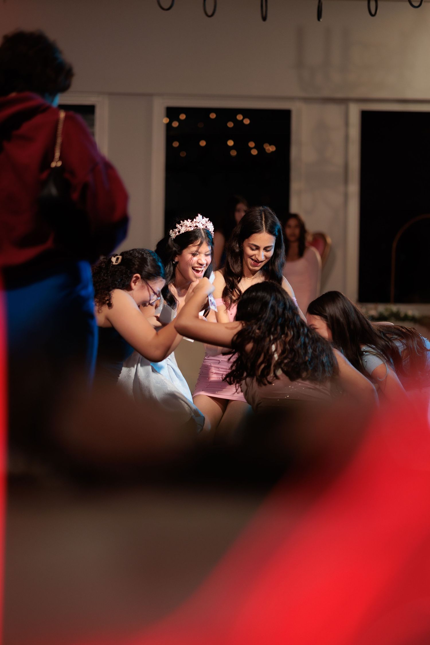 A dimly lit indoor celebration with dancing silhouettes and festive lighting.